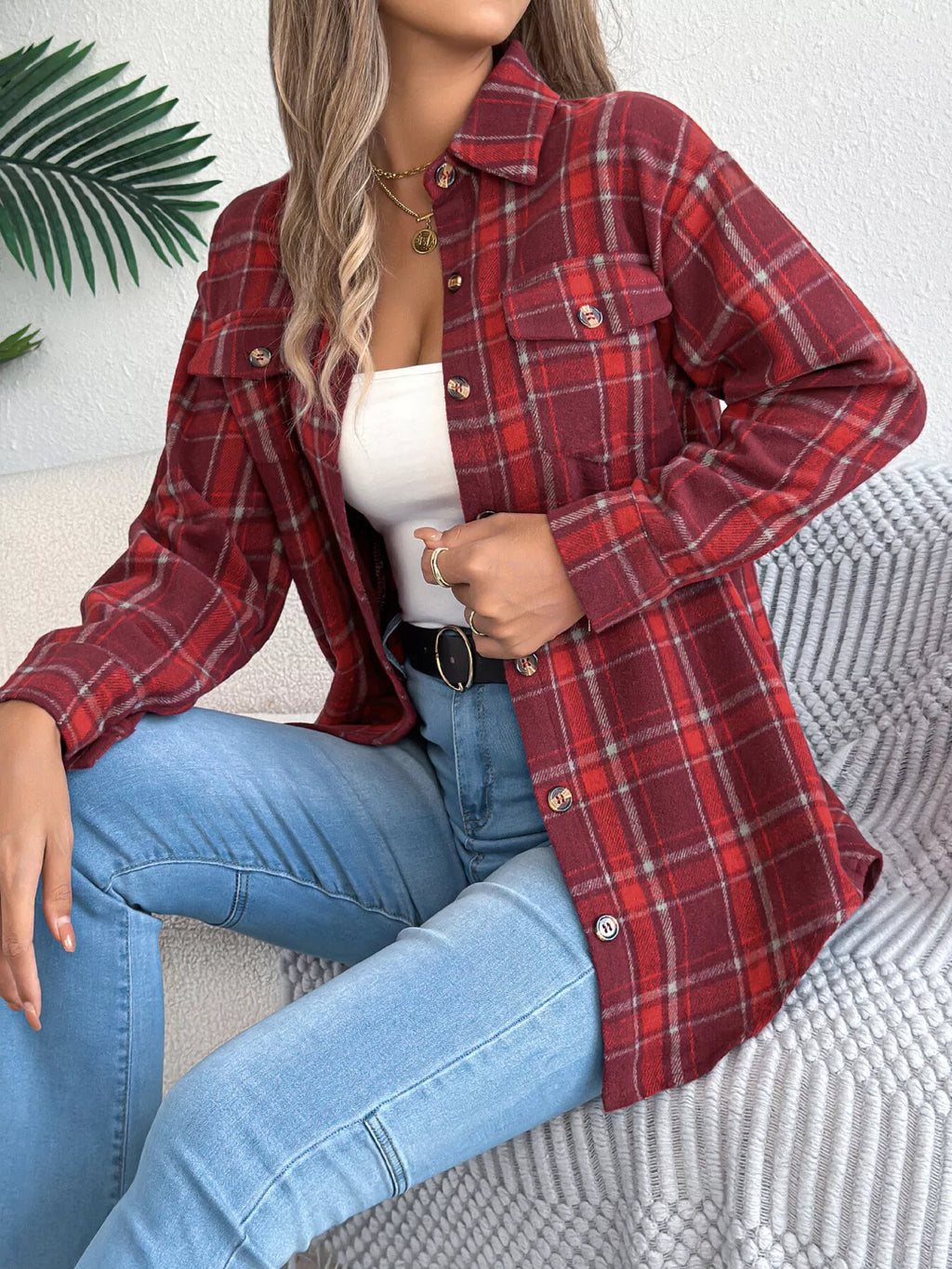 Red plaid button-down shacket with chest pockets, modeled seated with jeans.
