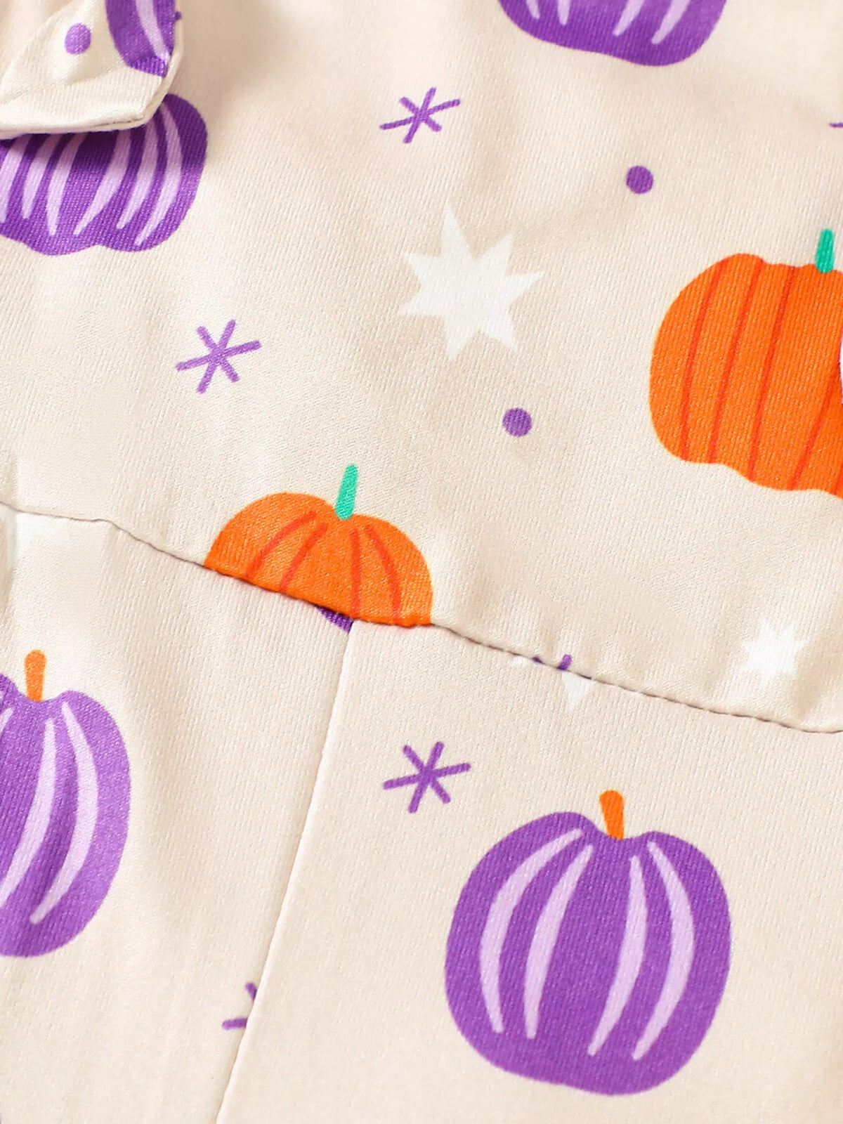 Close-up of the cream overalls' orange and purple pumpkin print at the waist seam.