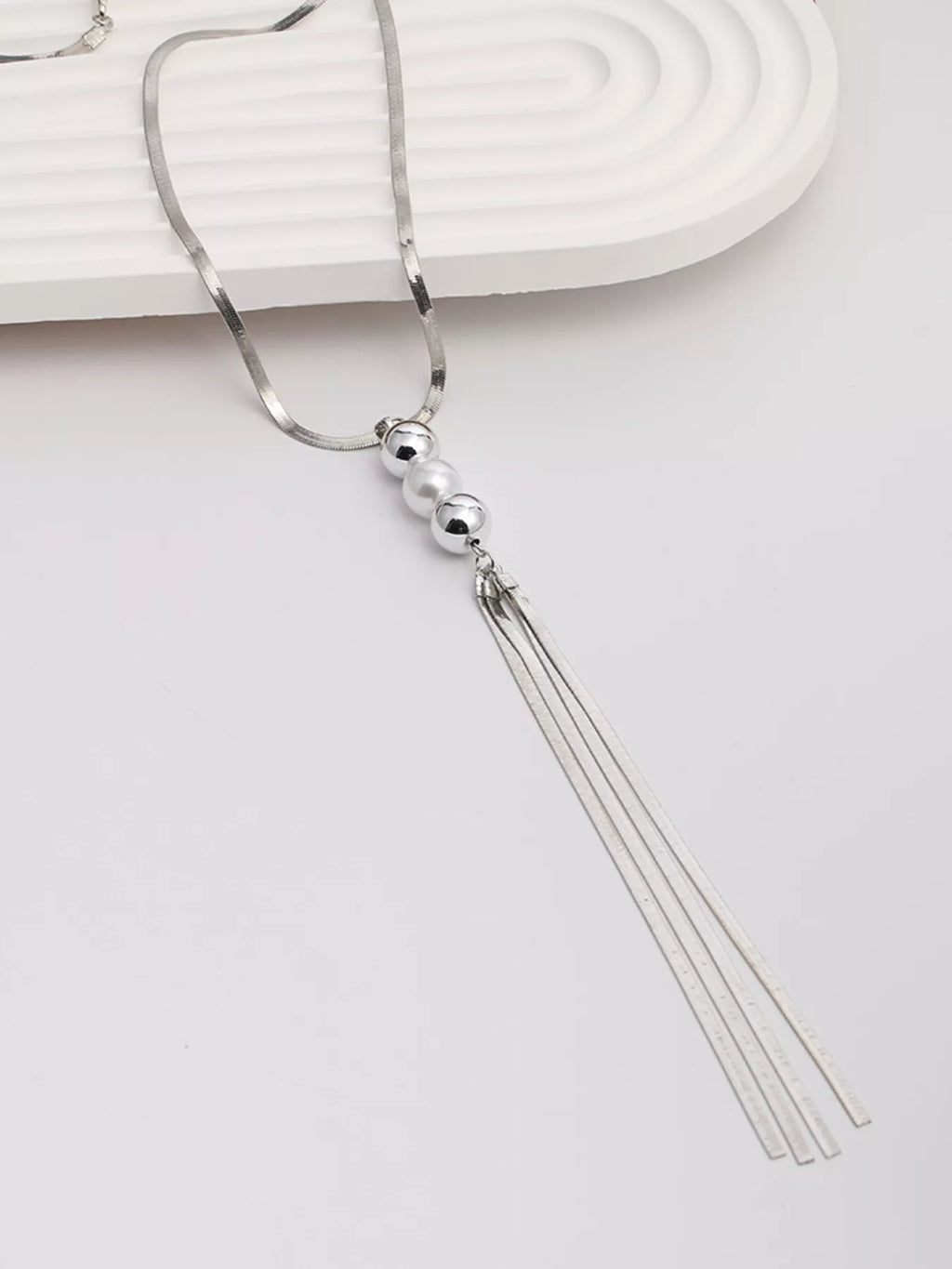 Long silver-tone necklace with bead accents and chain tassel — tassel detail