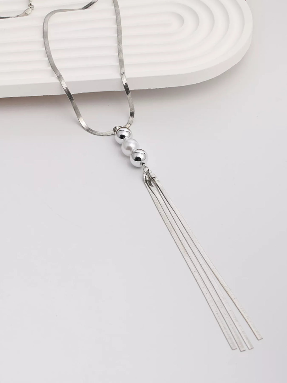 Long silver-tone necklace with bead accents and chain tassel — tassel detail