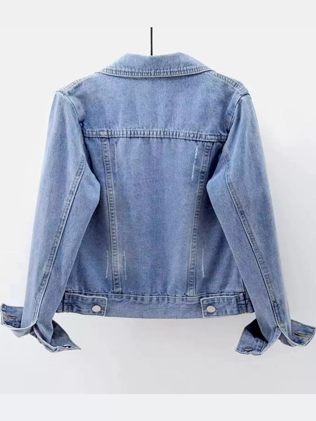 Rear view of the light-wash denim jacket displayed on a hanger.