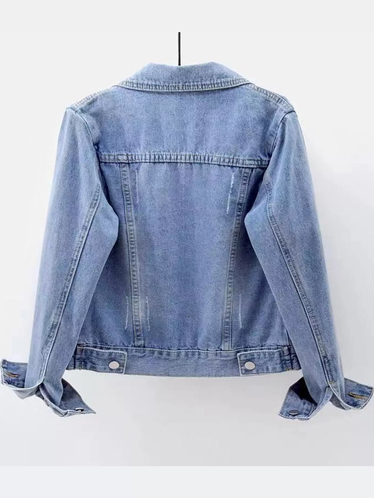 Rear view of the light-wash denim jacket displayed on a hanger.