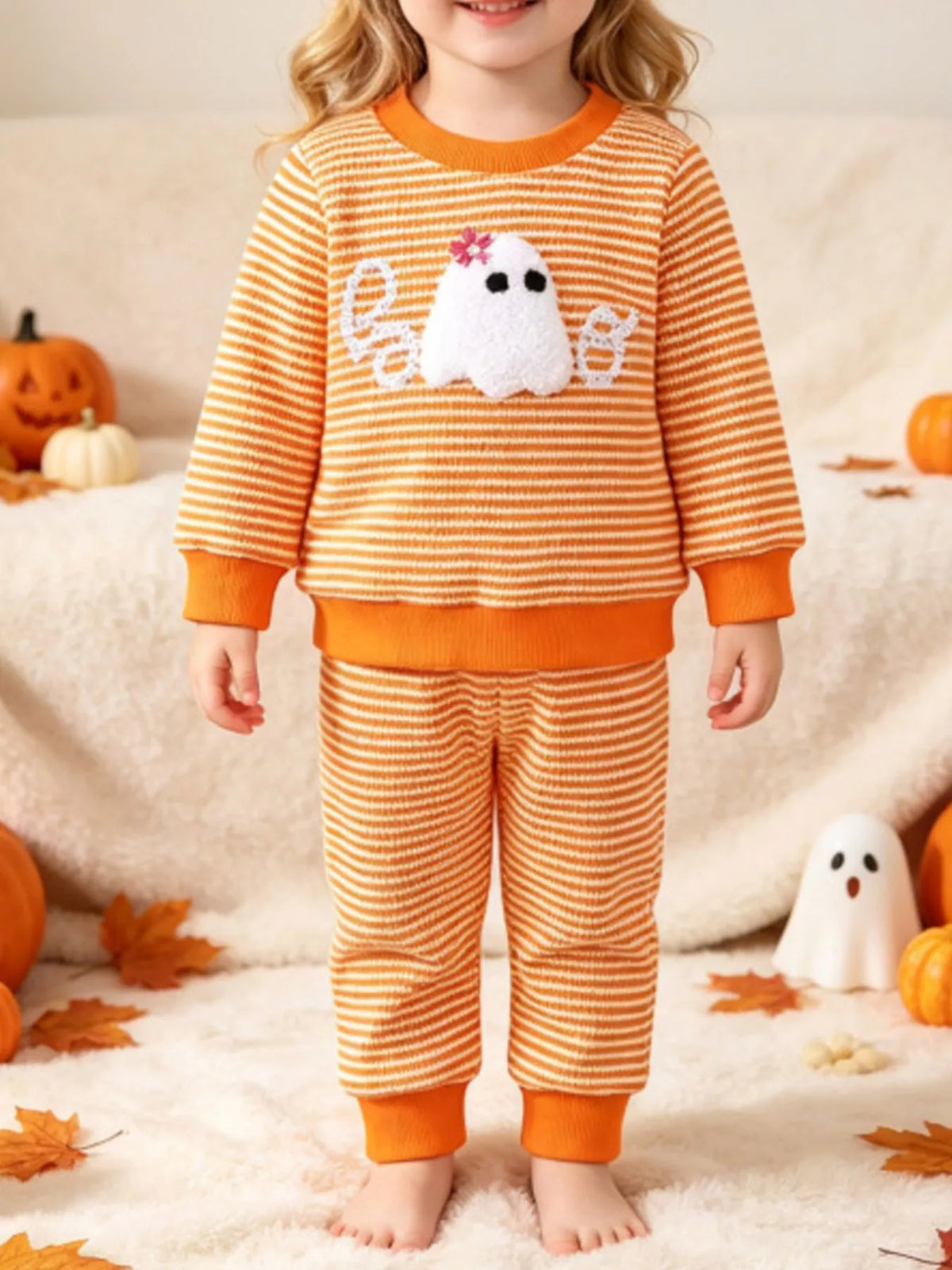 Orange striped ghost graphic pajama top and matching pants worn by a child