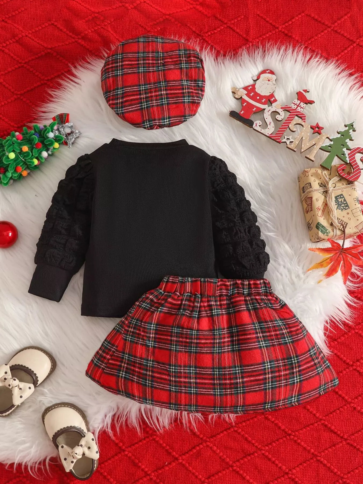 Back flat lay of the black top, red plaid skirt and matching beret.