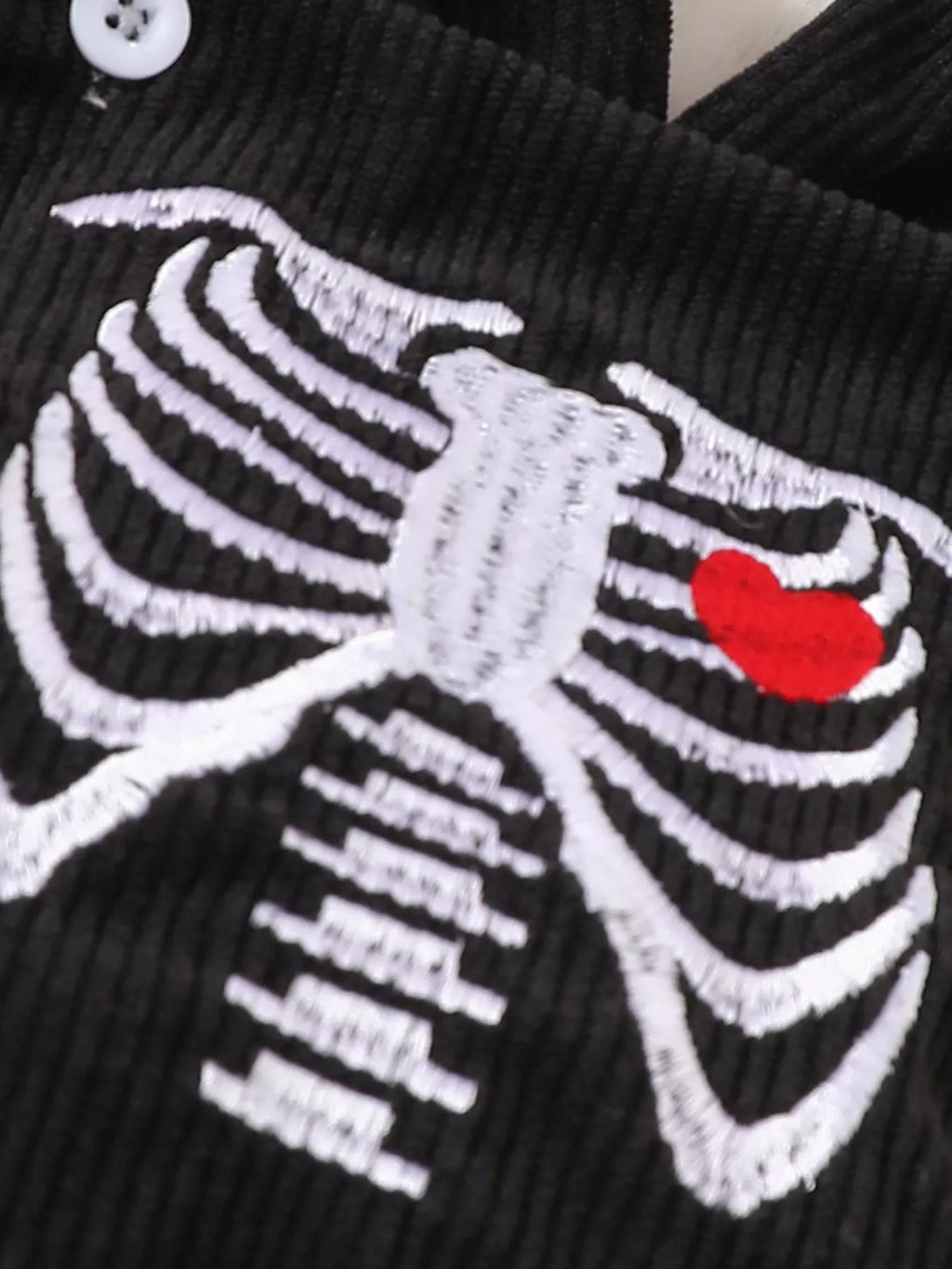 White skeleton print with a red heart on the black baby bodysuit