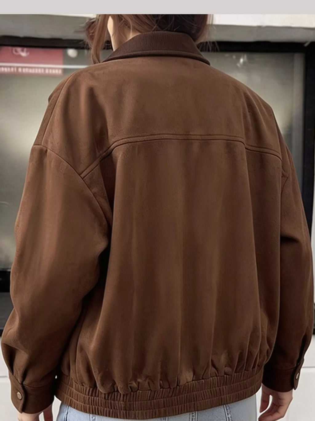 Back view of the brown jacket with a gathered hem and dropped shoulders.