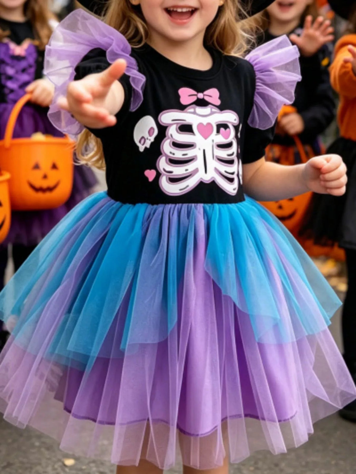 Child wearing a black skeleton graphic dress with purple sleeves and blue-and-purple tulle skirt.