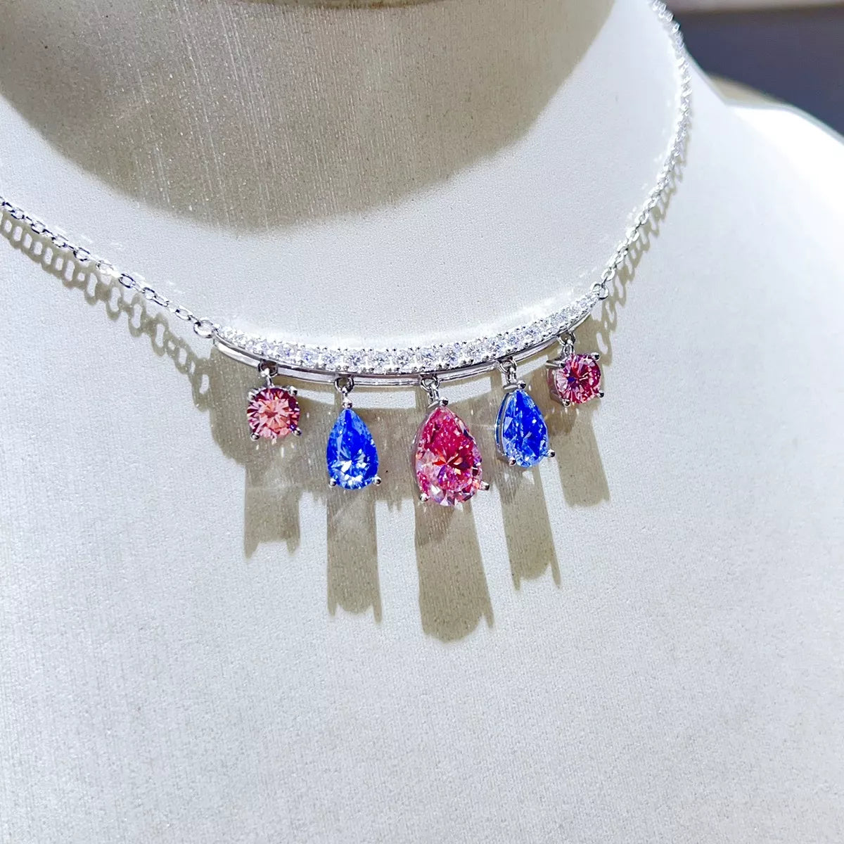 Silver-tone necklace with blue and pink teardrop stone pendants — detail view
