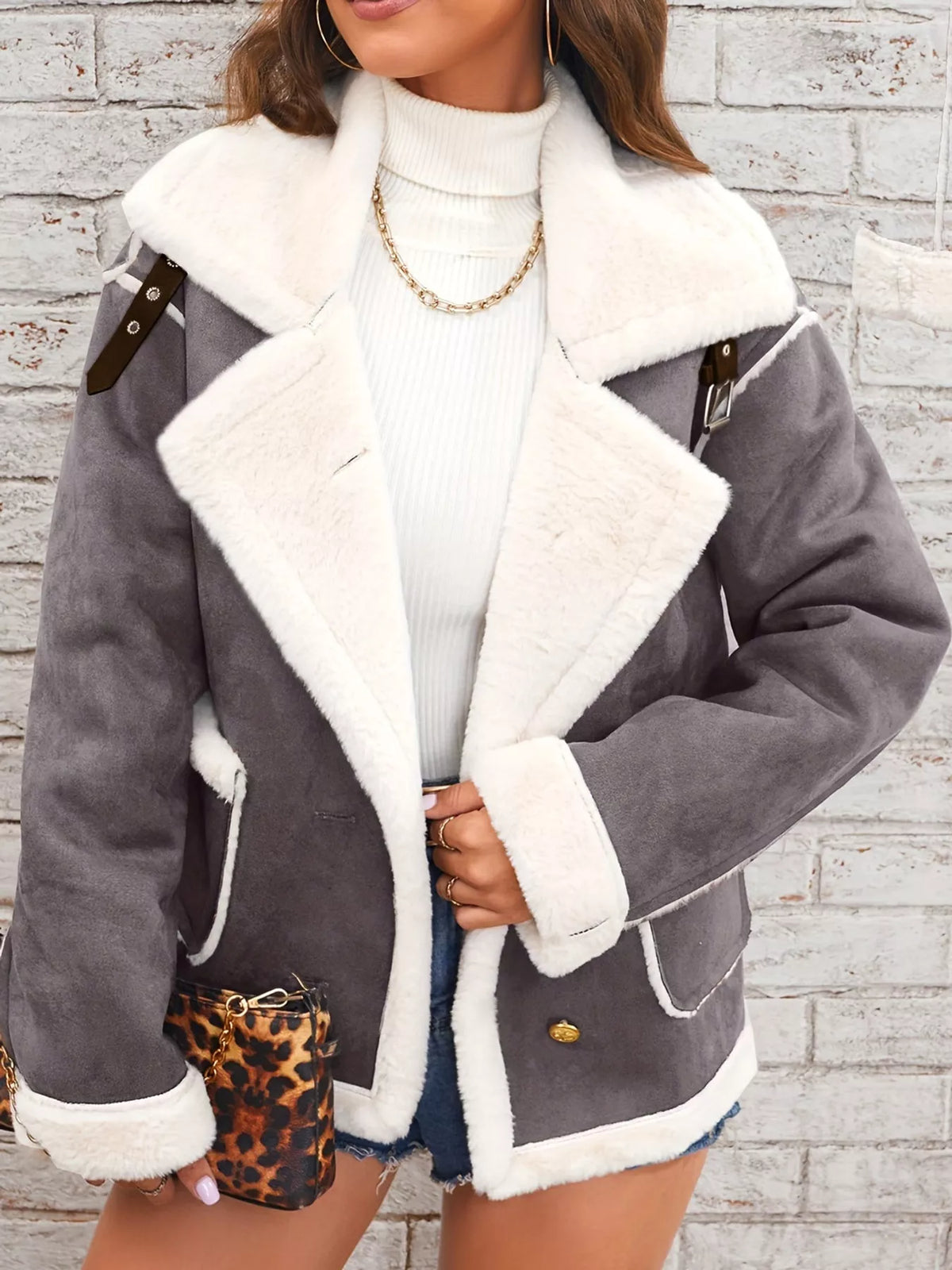 Dark-gray jacket with wide white plush lapels, contrast trim and front pockets, front view modeled holding the lapel.
