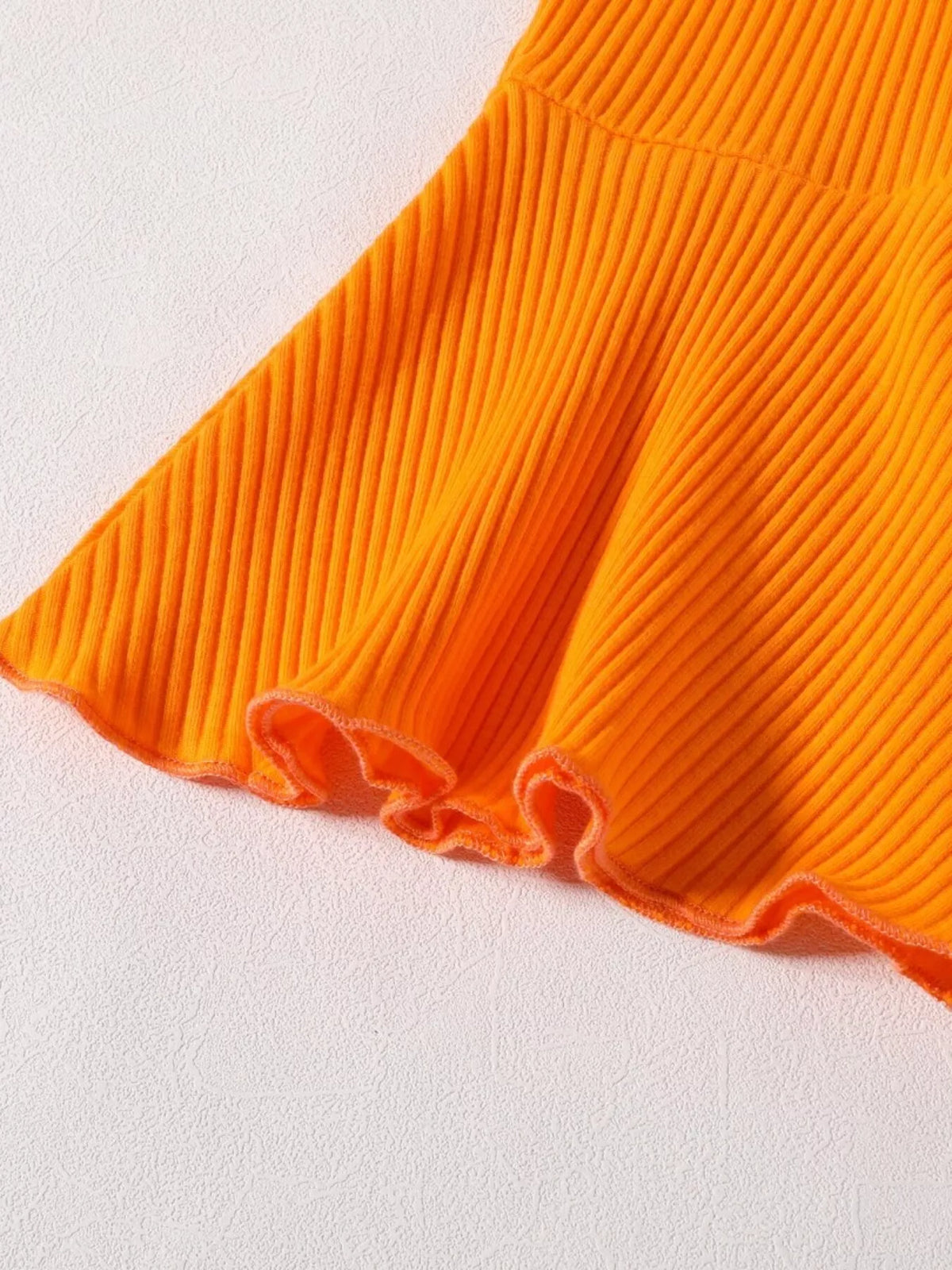 Close-up of the orange pants' flared ribbed hems.
