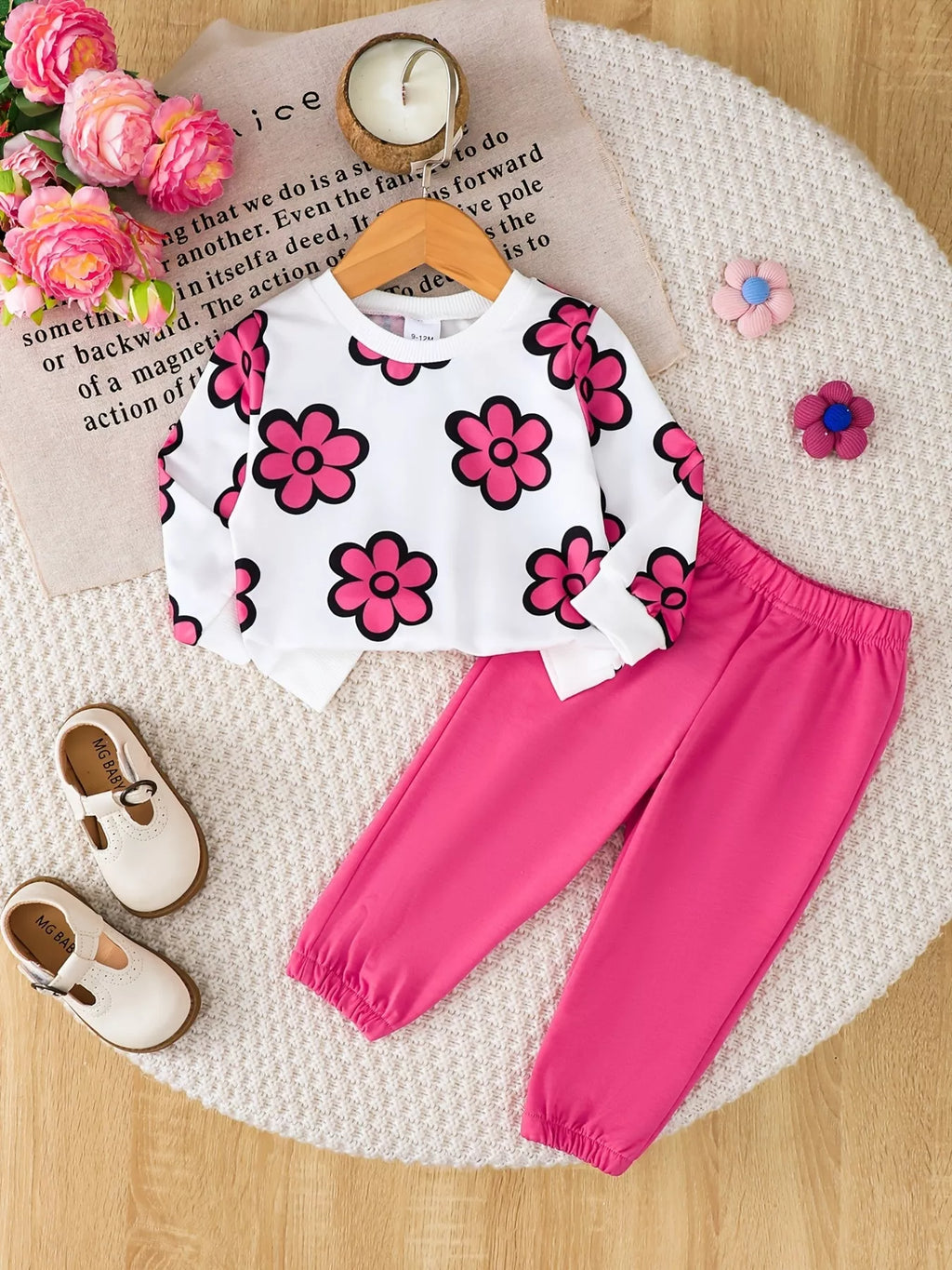Flat lay of a white pink-flower sweatshirt and bright pink jogger pants.