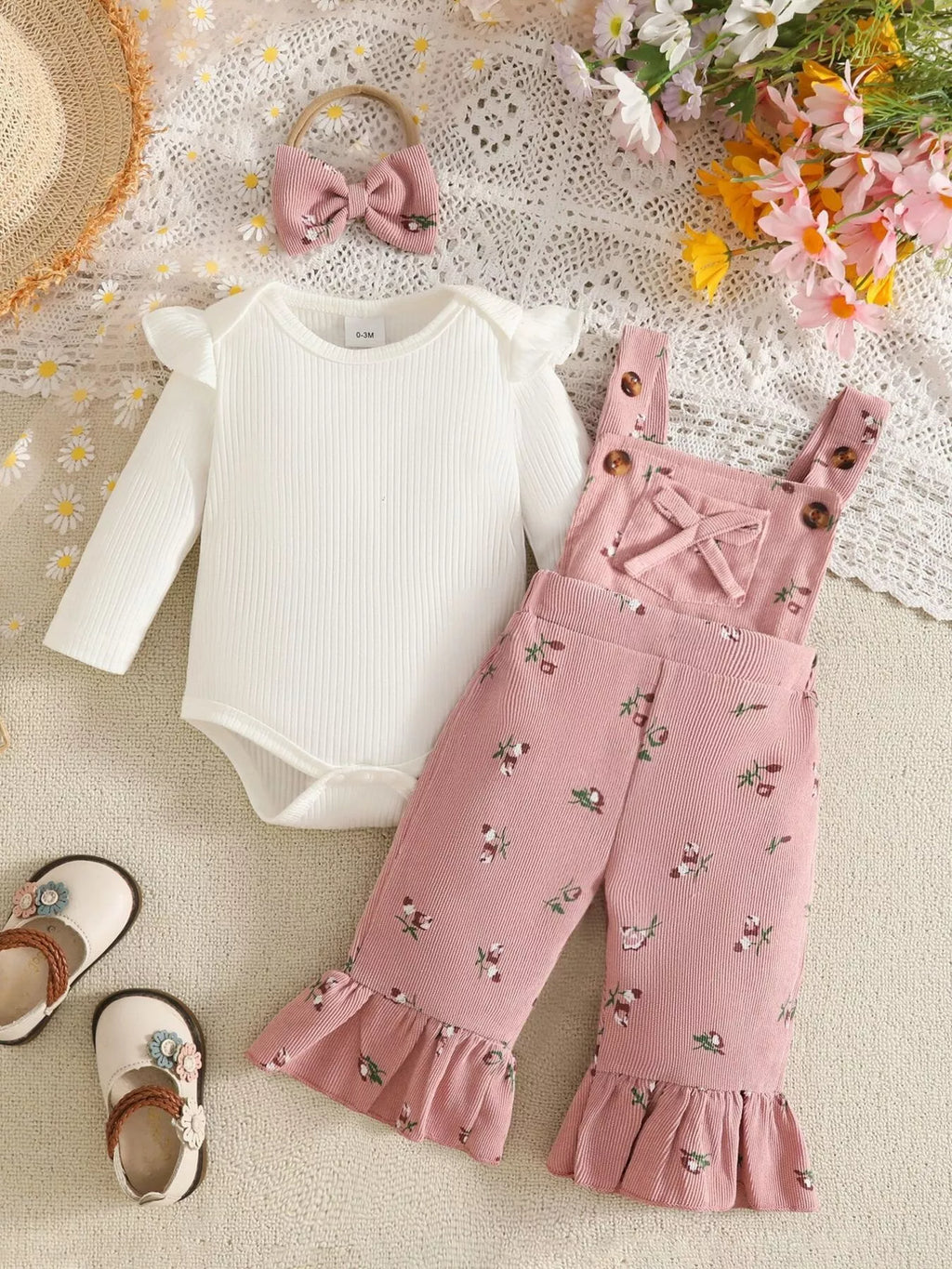 White ribbed baby bodysuit with pink bow-accented overalls and matching headband displayed flat