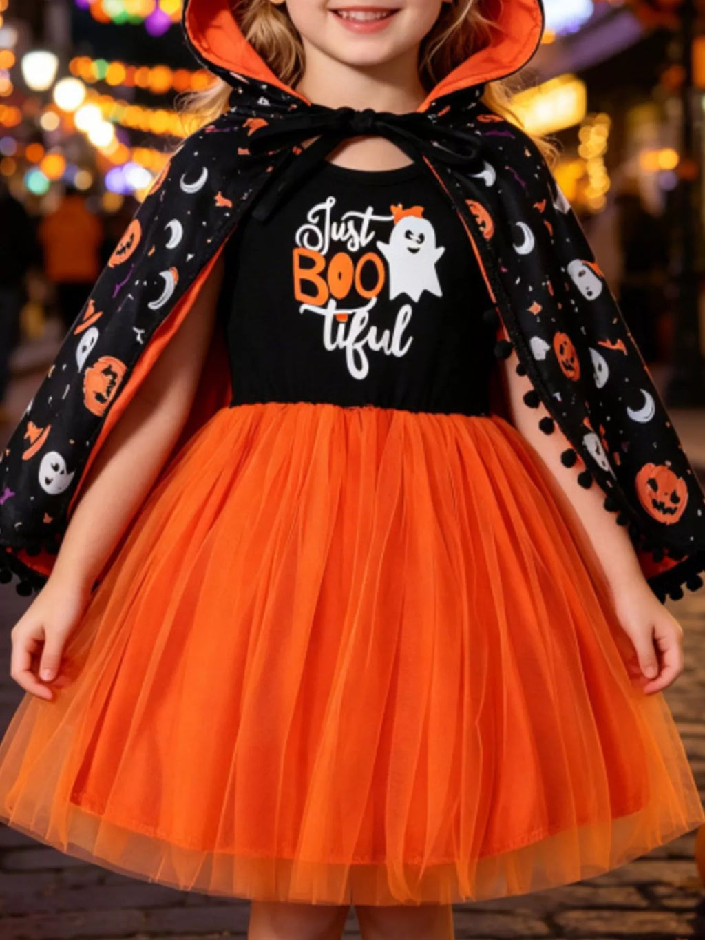 Child wearing a black Just Boo-tiful top, orange tulle skirt and Halloween-print cape.