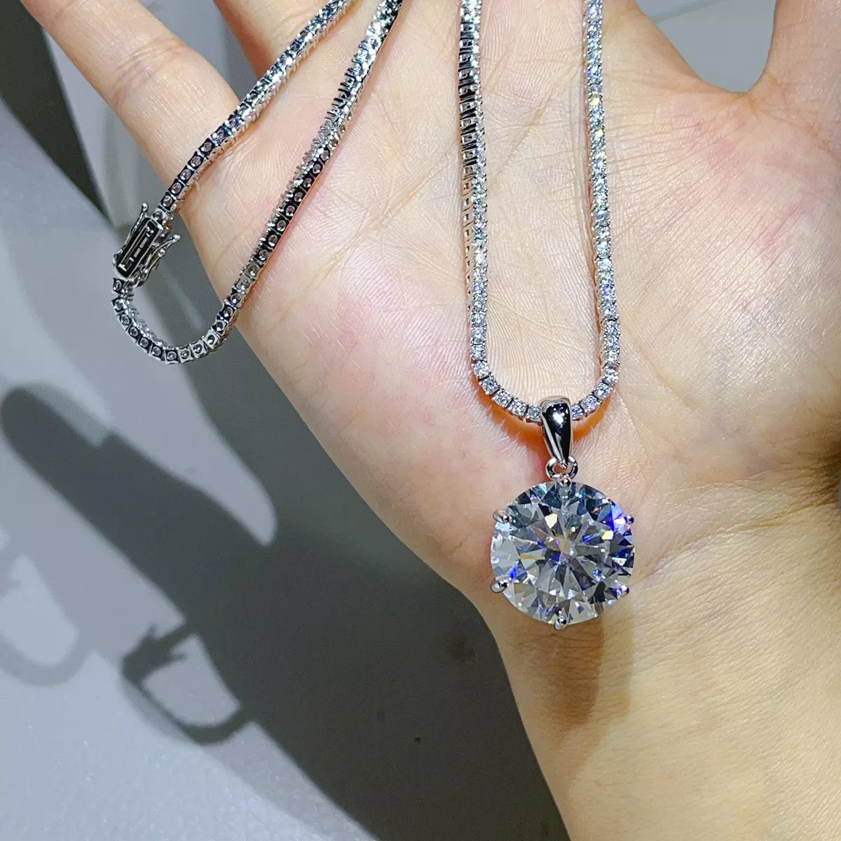 Silver-tone necklace with a round clear stone pendant — detail view