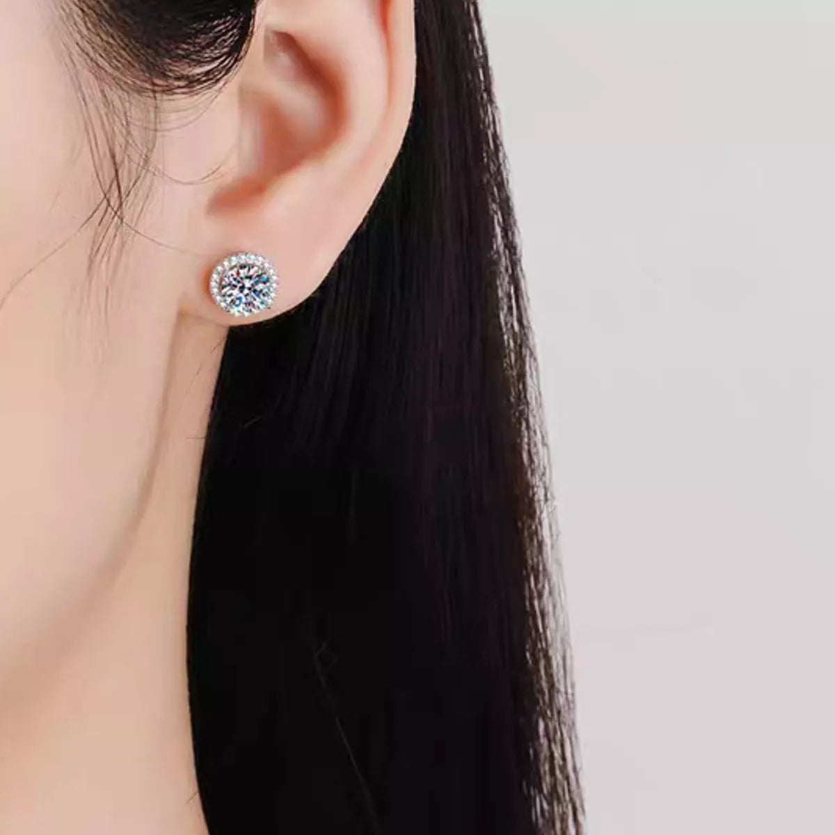 Silver-tone round halo stone stud earrings worn on a model