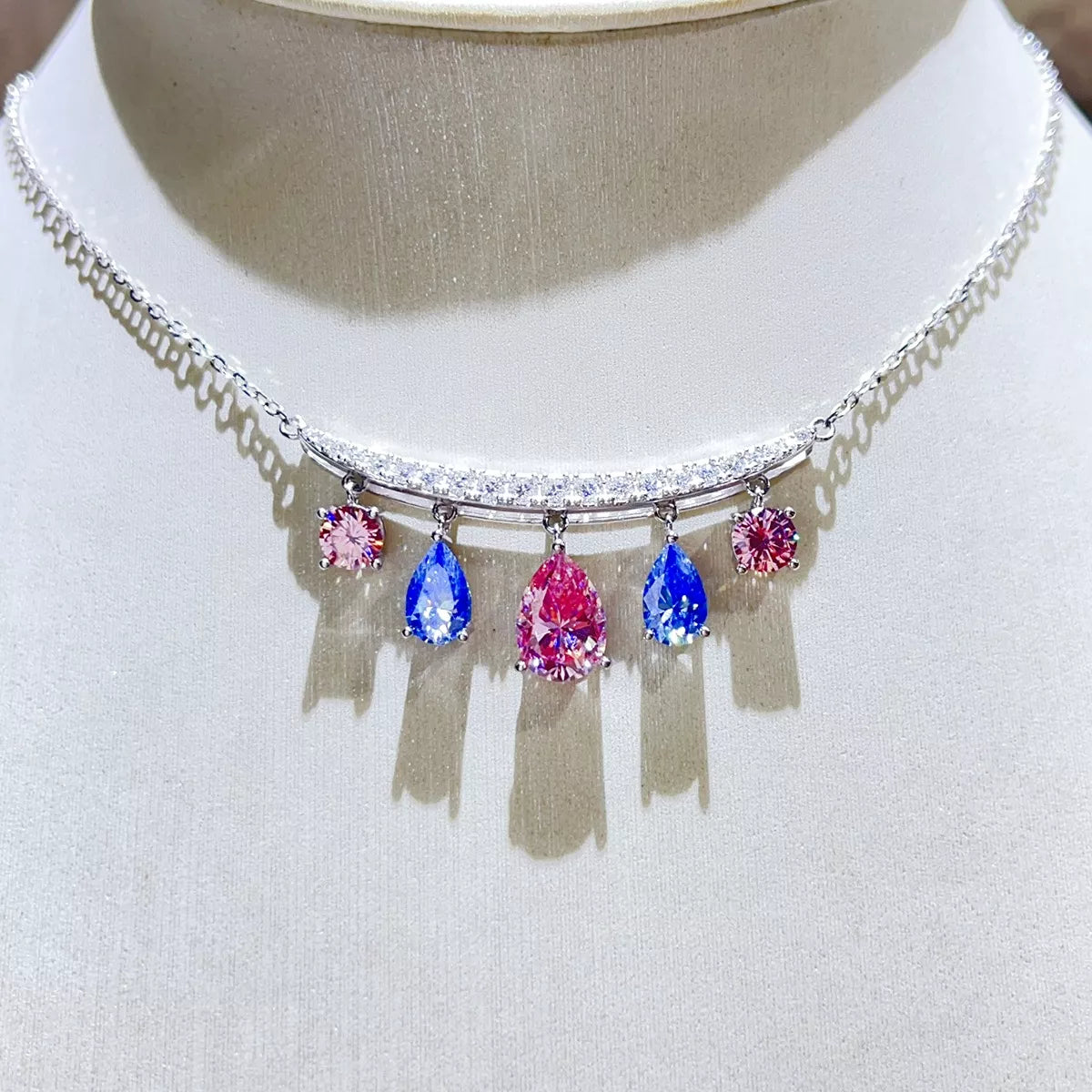 Silver-tone necklace with blue and pink teardrop stone pendants — detail view