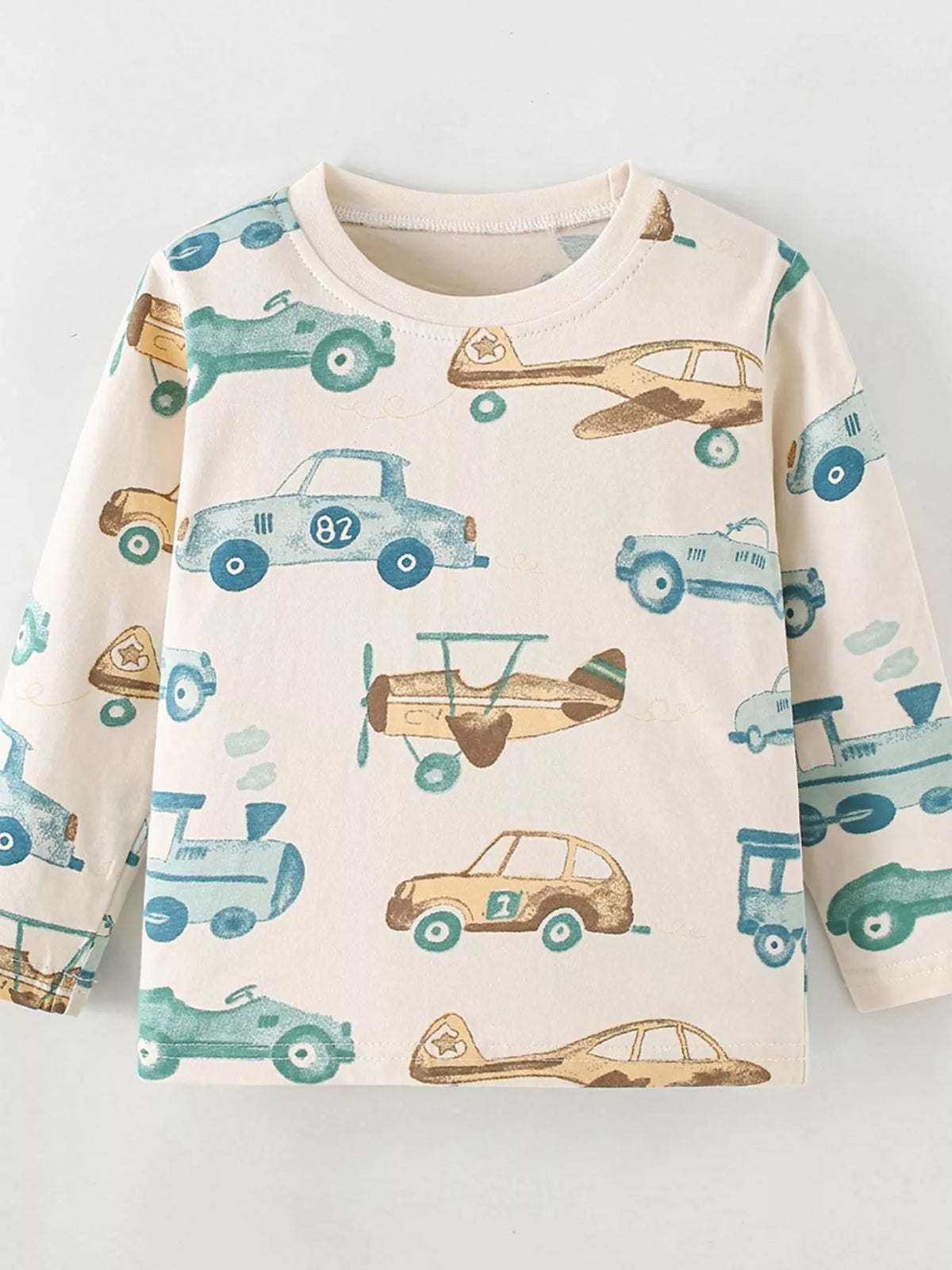 Front product view of the cream children's car-and-airplane print shirt.