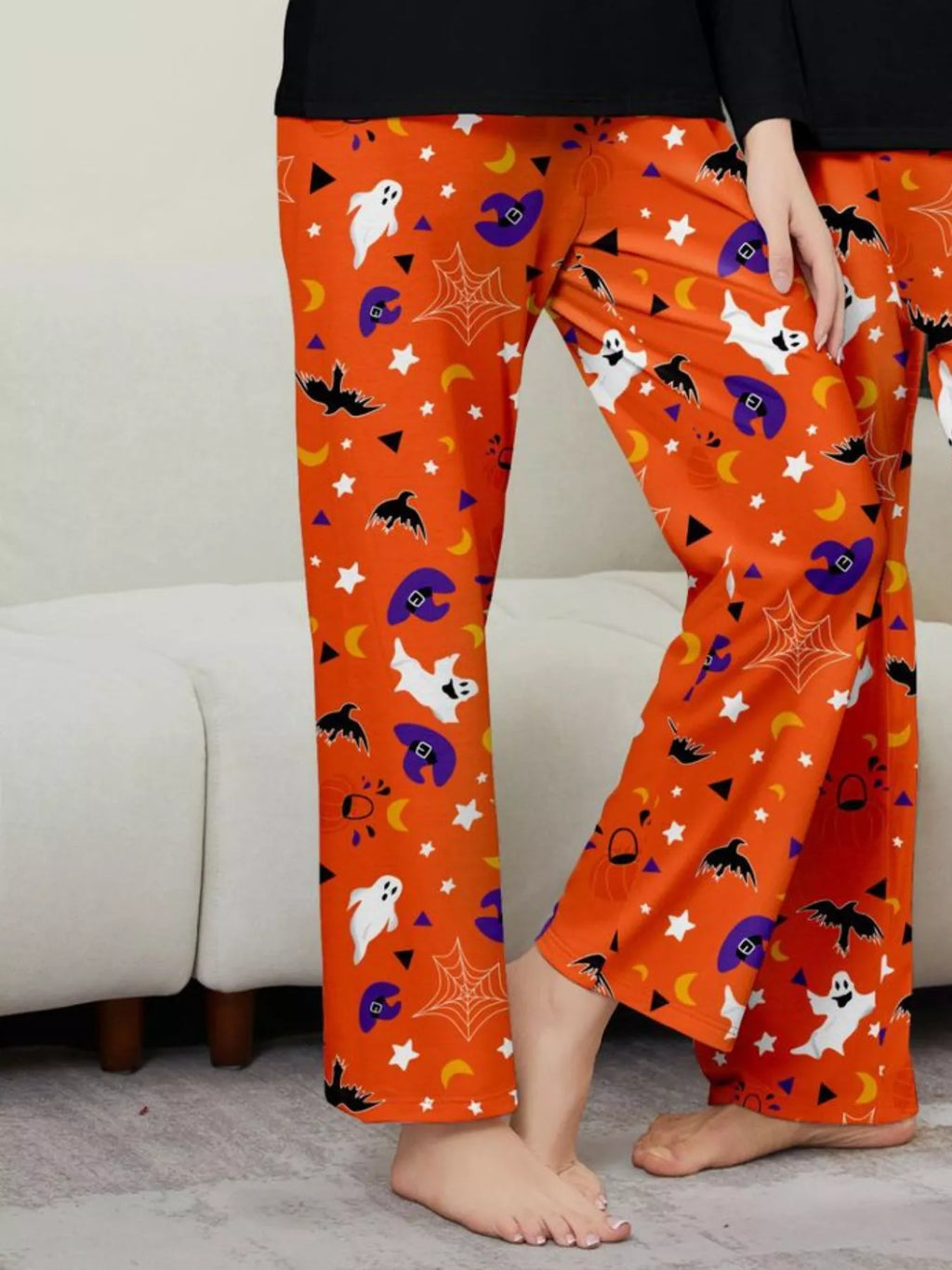 Woman modeling orange Halloween-print pajama pants.