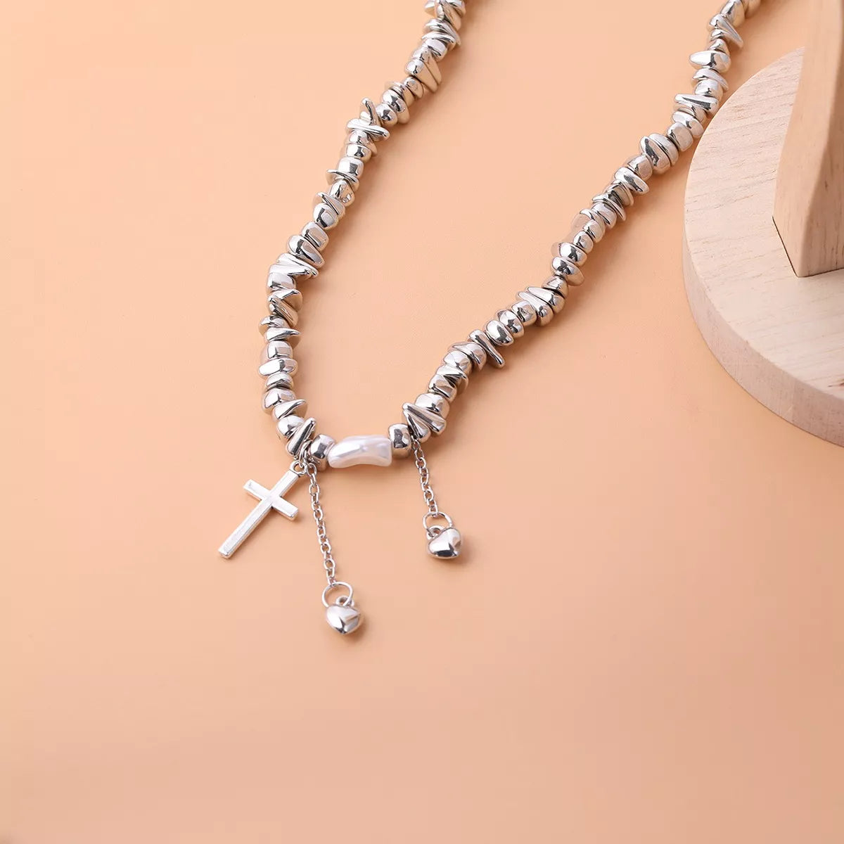Chunky silver-tone chain necklace with cross and dangling charms — detail view