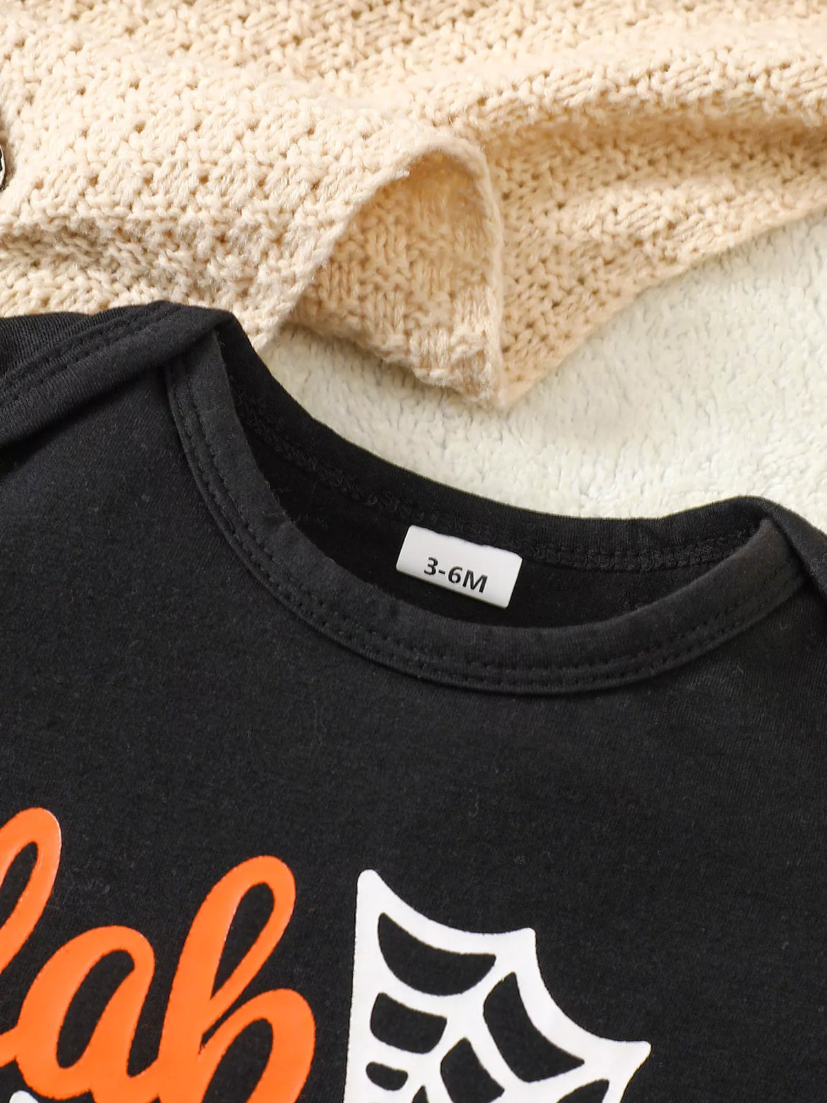Close-up of the black Halloween top's ribbed crew neckline.