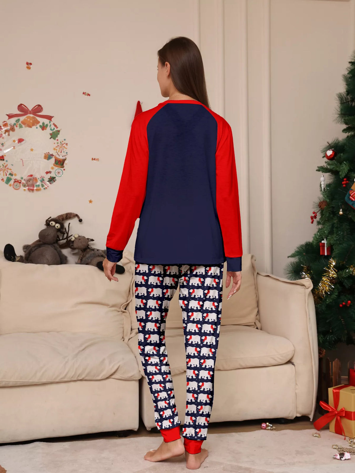 Navy and red Christmas graphic pajama top with matching festive-print pants worn by an adult — back view