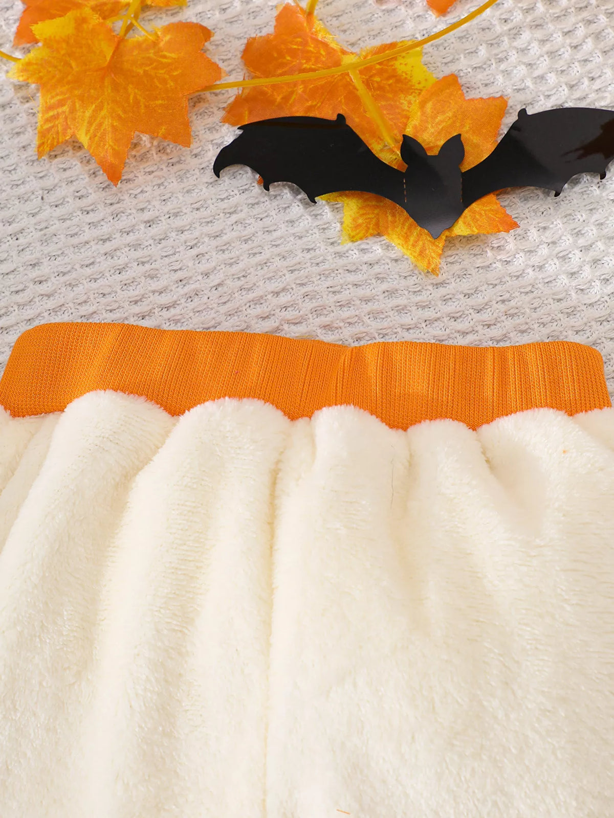 Orange waistband and soft cream fabric of the children’s pants