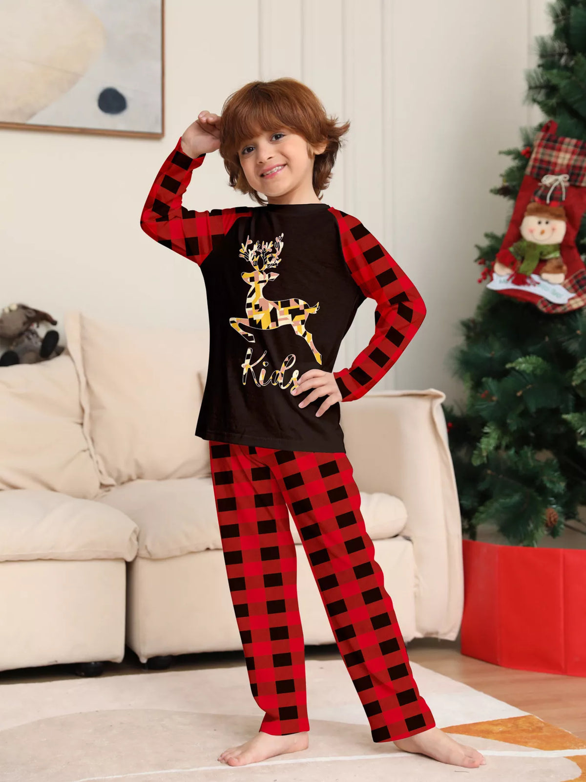 Child modeling the black reindeer graphic pajama top and red plaid pants.