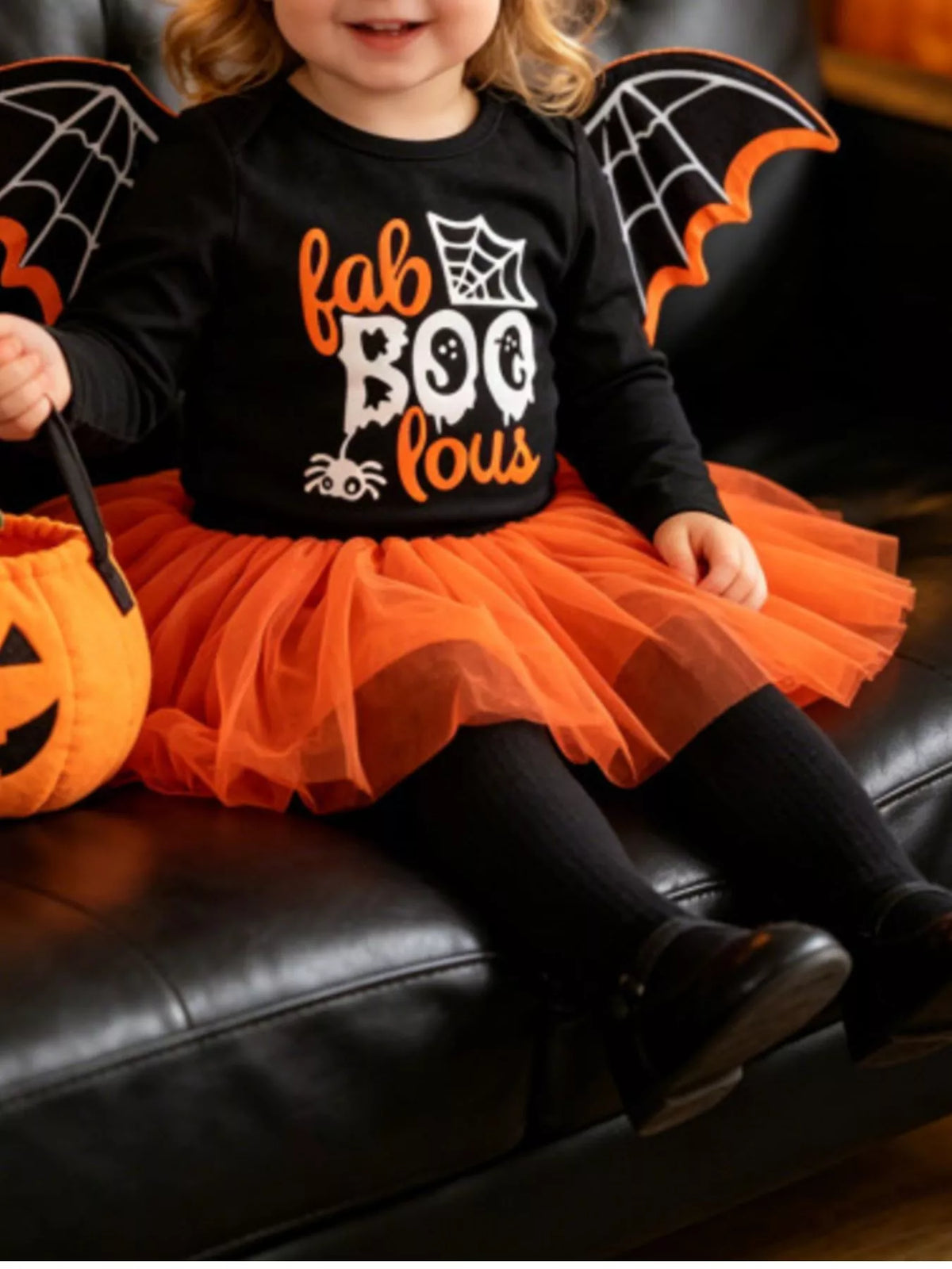 Child wearing a black Fab Boo Lous top, orange tulle skirt and bat-wing shoulder details.
