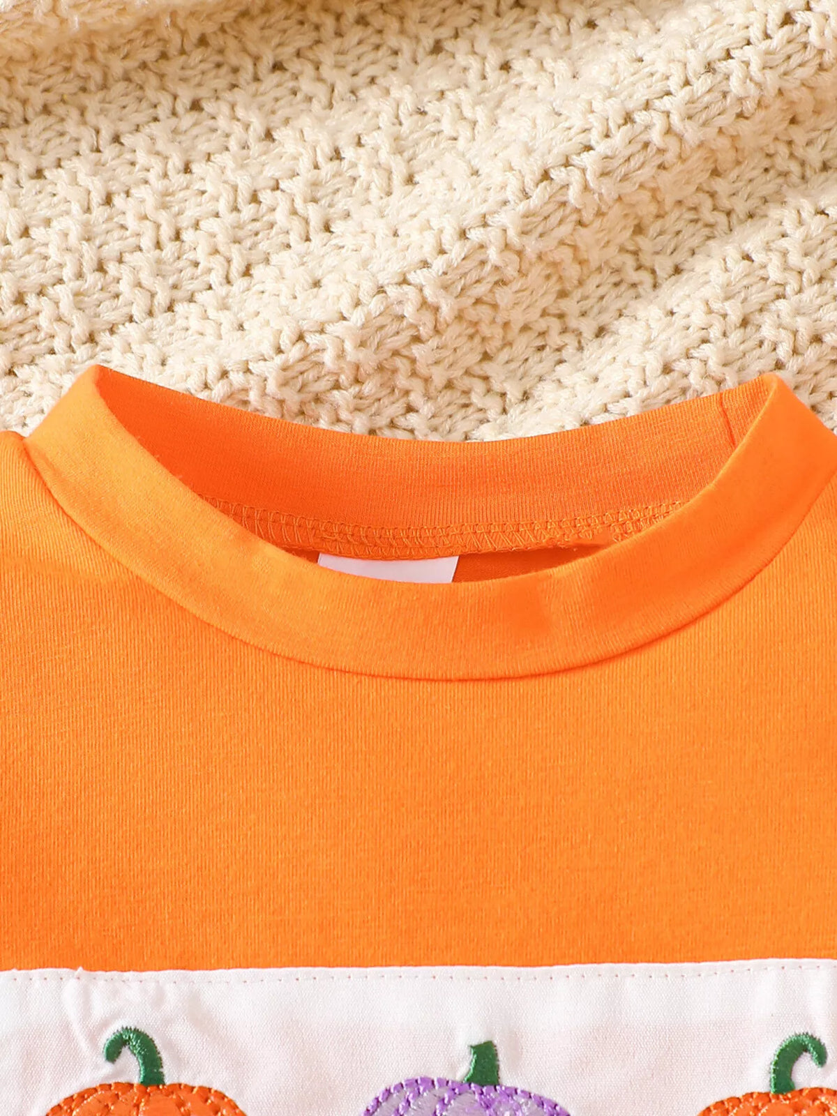 Close-up of the orange pumpkin top's ribbed neckline.