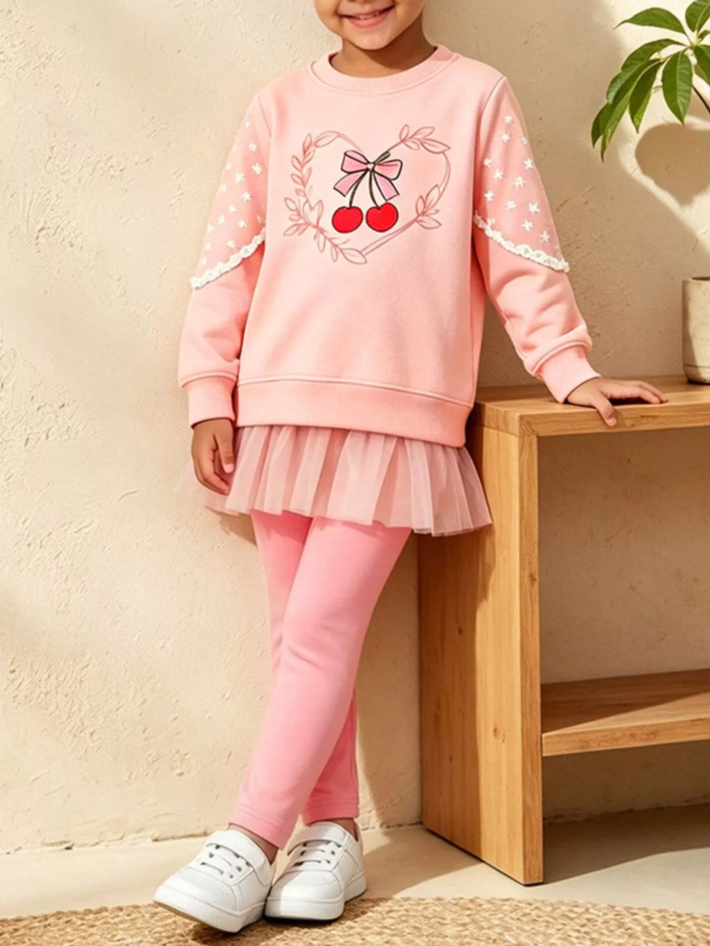 Front view of a child modeling the pink cherry graphic sweatshirt and leggings set.