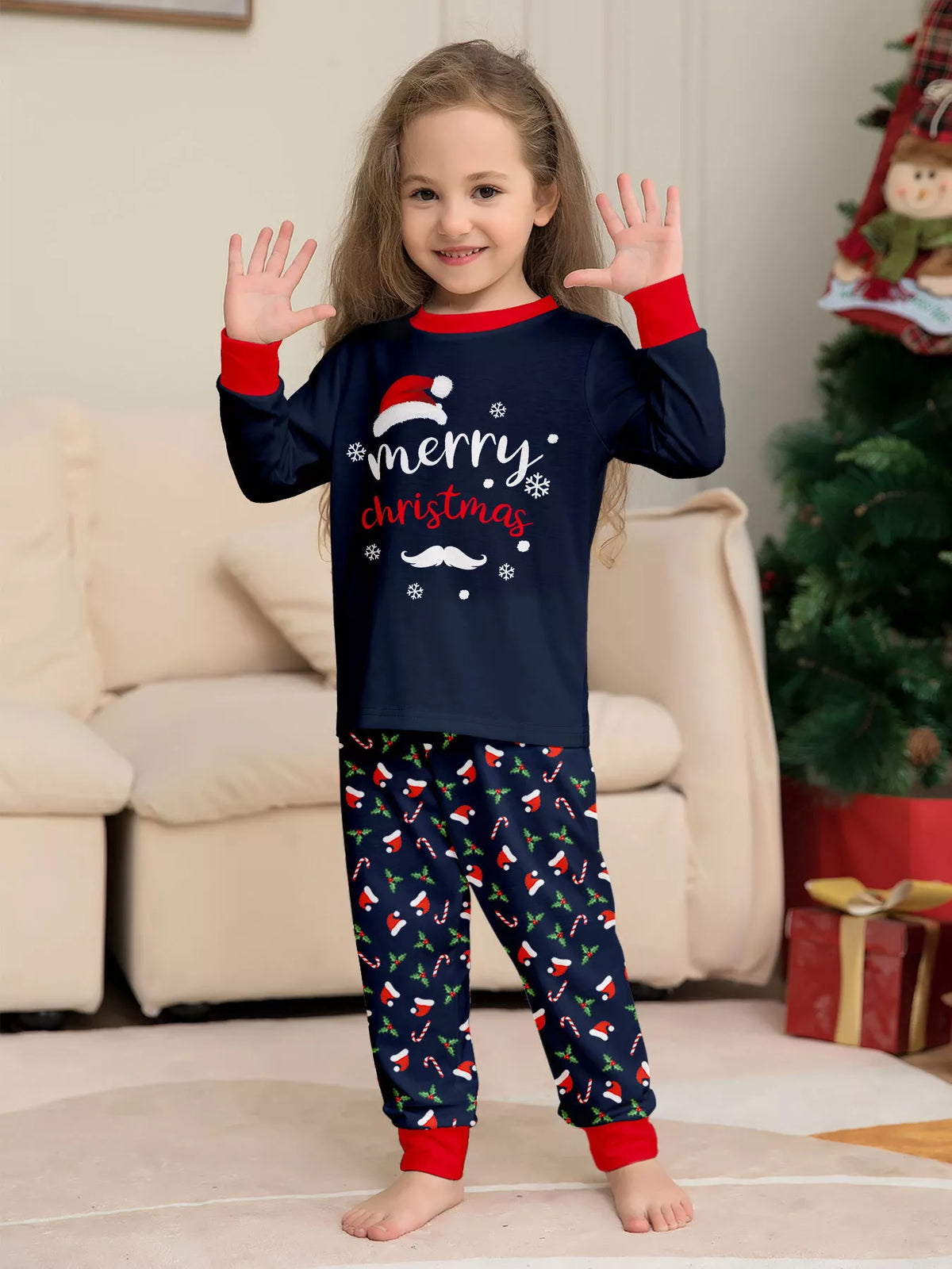 Child wearing a navy Merry Christmas top with red cuffs and matching printed pants.