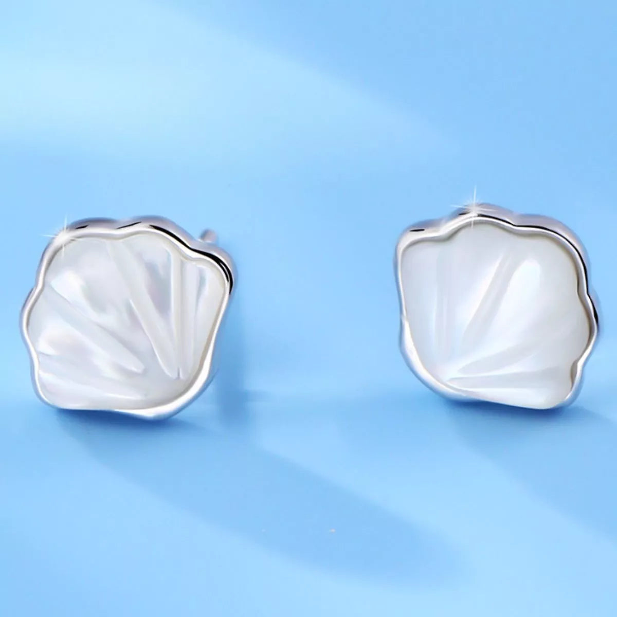 Silver-tone shell-shaped stud earrings with white centers — detail view