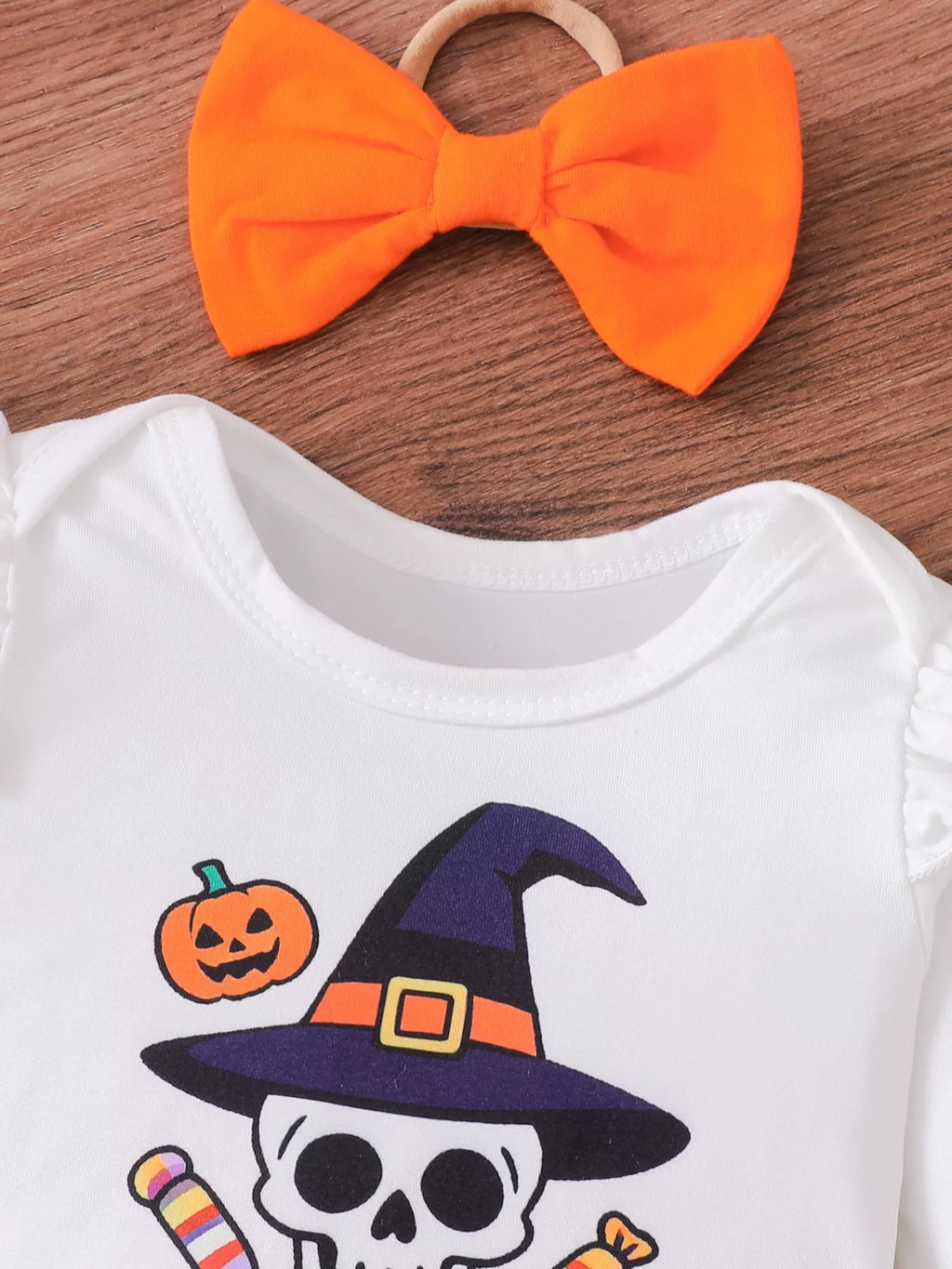 Close-up of the orange bow and white skull graphic bodysuit neckline.