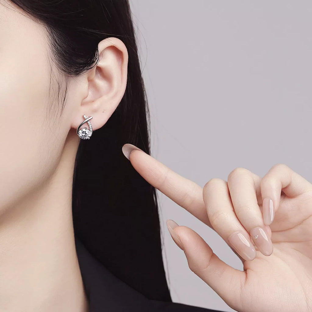 Silver-tone open teardrop earrings with round clear stones worn on a model