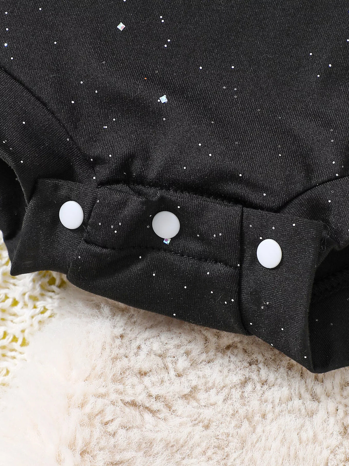 Snap fasteners on the black baby bodysuit