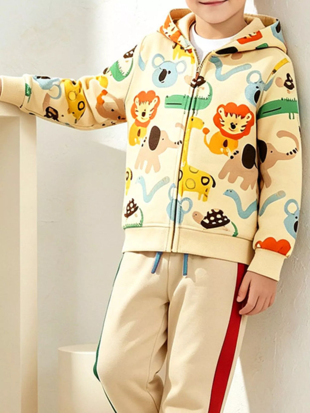Child modeling the animal-print zip-up hoodie and cream pants.