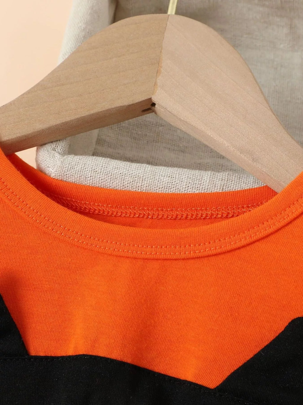 Close-up of the orange dress's ribbed crew neckline.