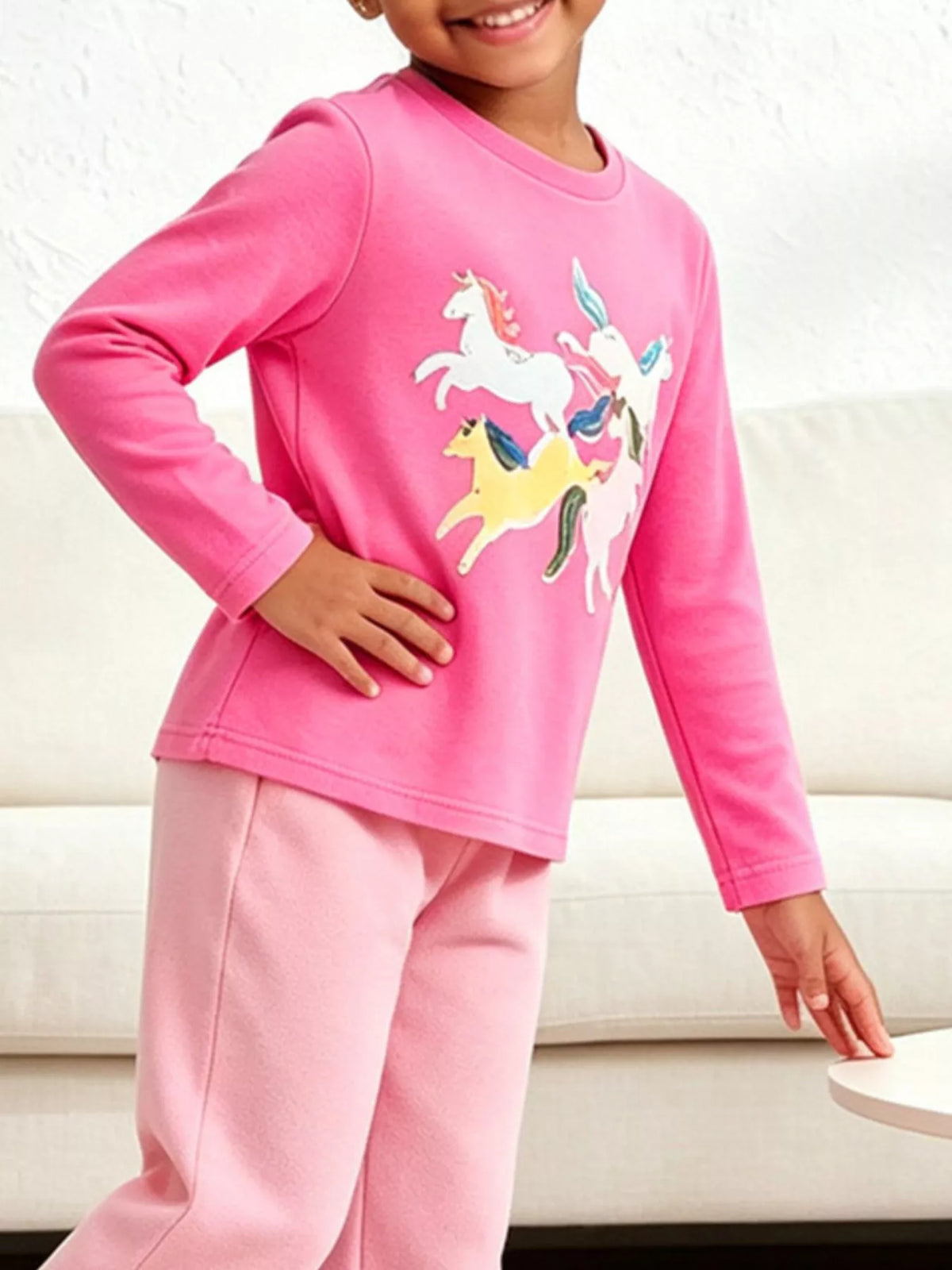 Children’s pink long-sleeve T-shirt with colorful unicorn graphics worn by a child