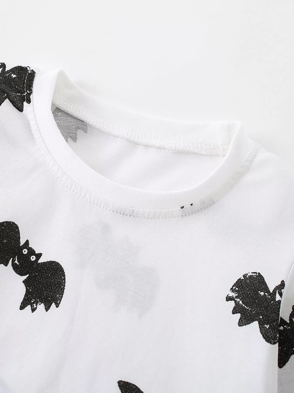 Close-up of the white bat-print top's crew neckline.