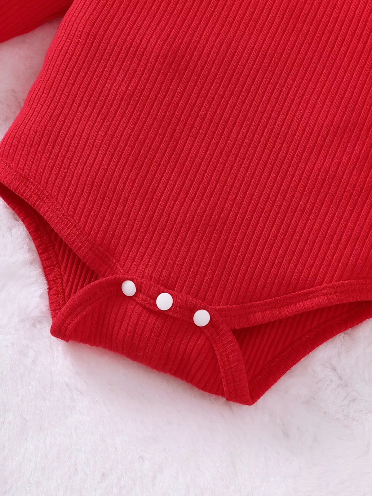 Close-up of the red ribbed baby bodysuit's three bottom snaps.