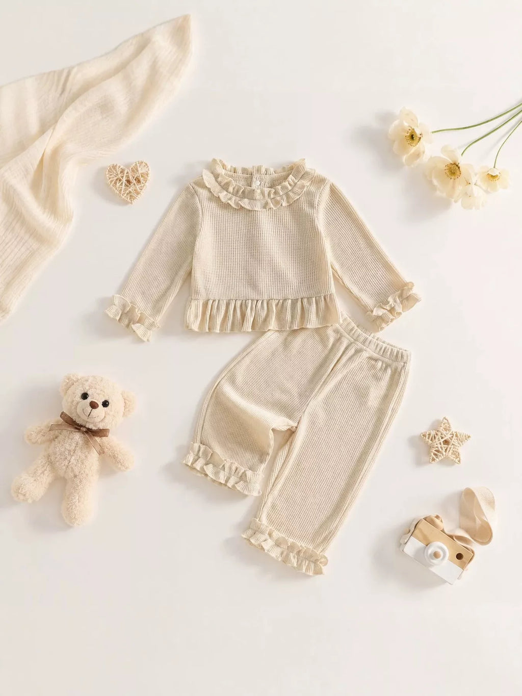Flat lay of the cream ruffle-neck peplum top and matching ruffle-hem pants.