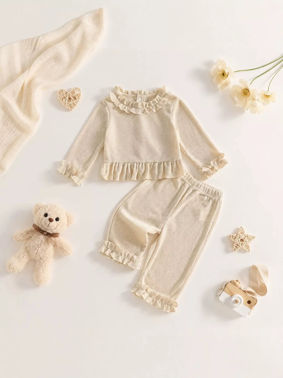 Flat lay of the cream ruffle-neck peplum top and matching ruffle-hem pants.