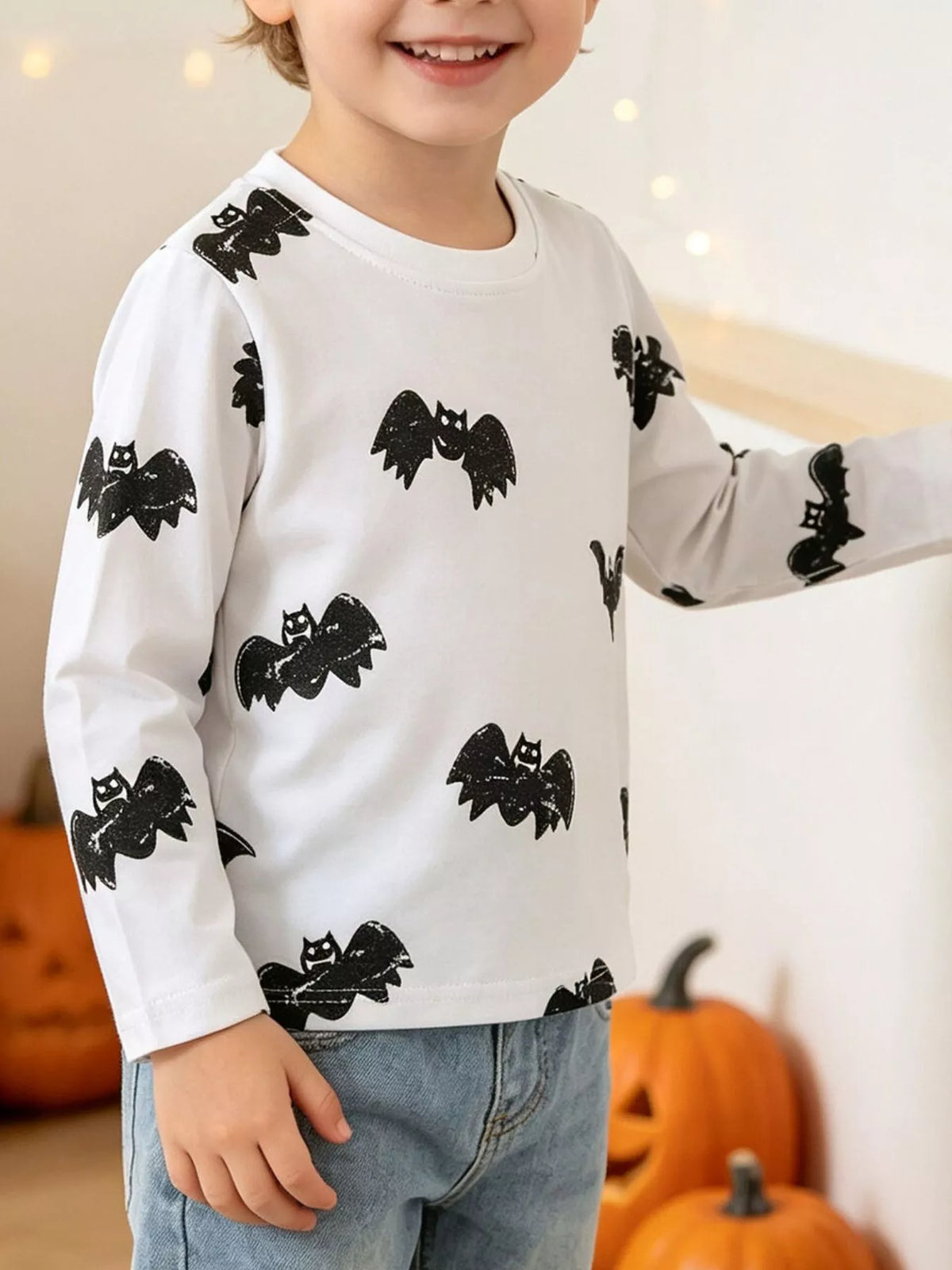 Child wearing a white long-sleeve top with black bat prints.