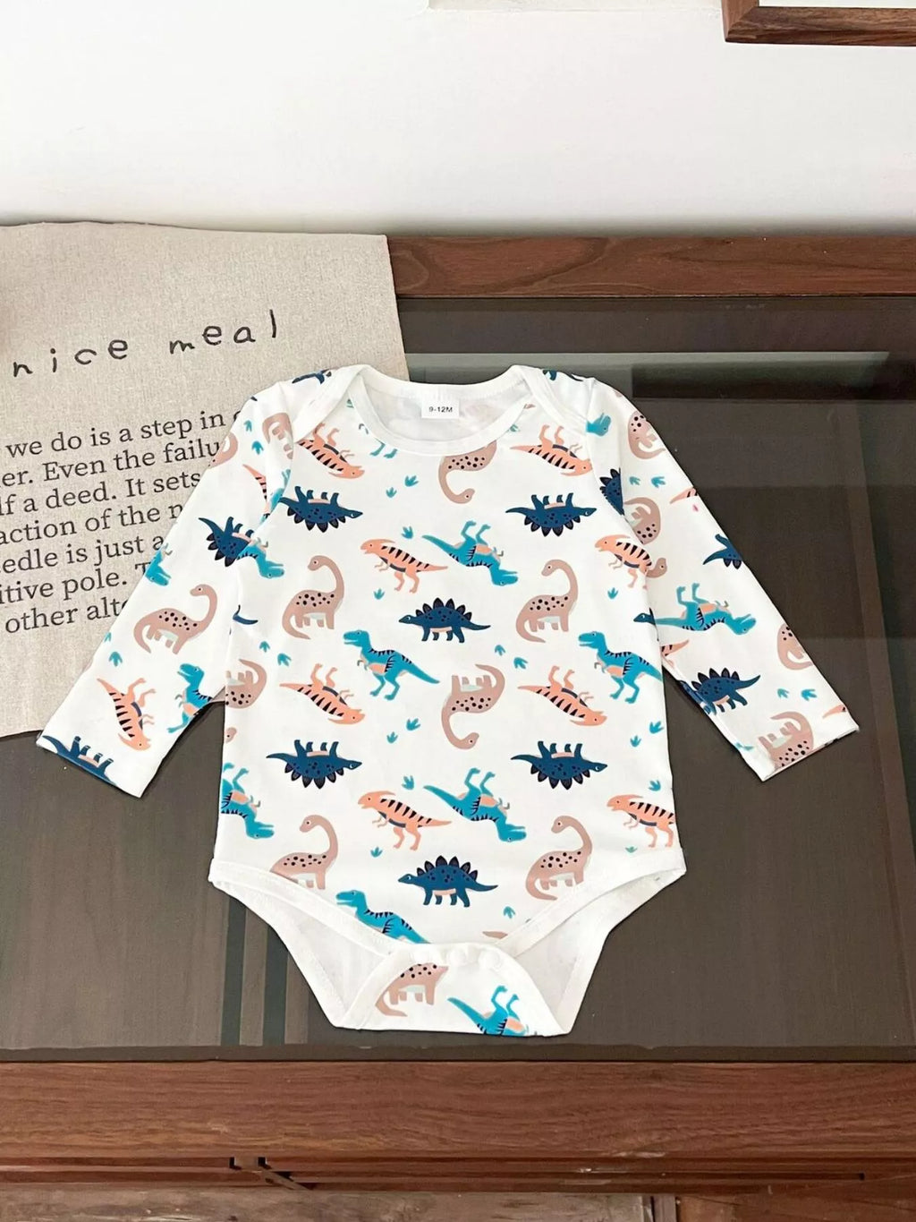 White long-sleeve baby bodysuit with colorful dinosaur print