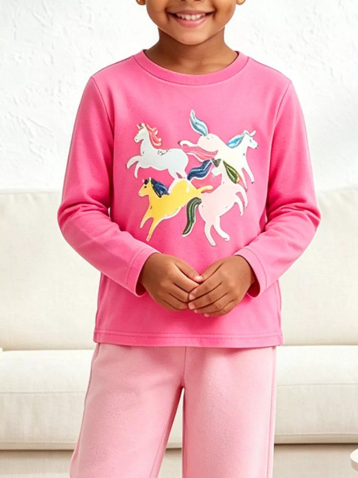 Children’s pink long-sleeve T-shirt with colorful unicorn graphics worn by a child