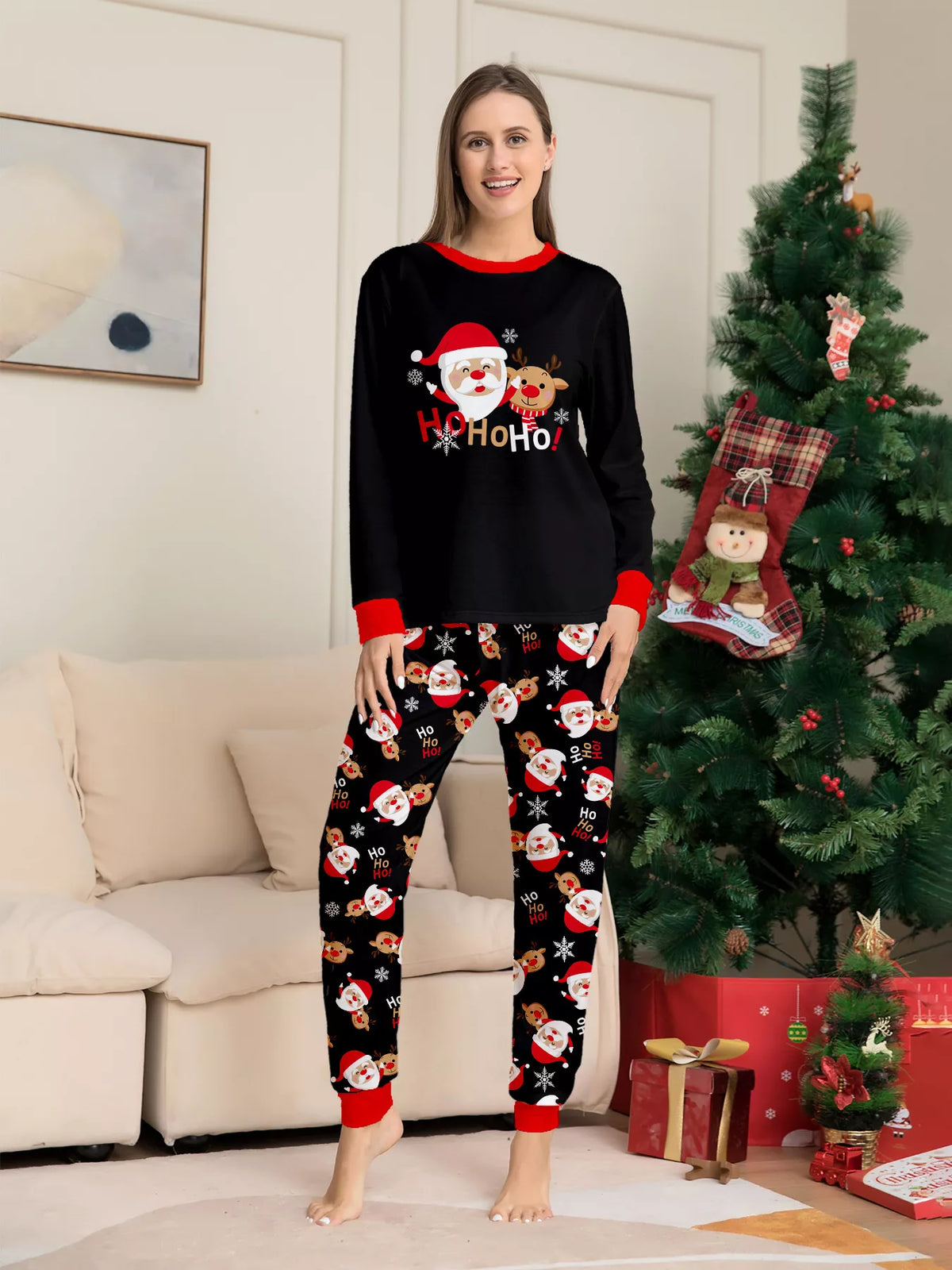 Woman wearing a black Ho Ho Ho Santa top and black Santa-print pajama pants.