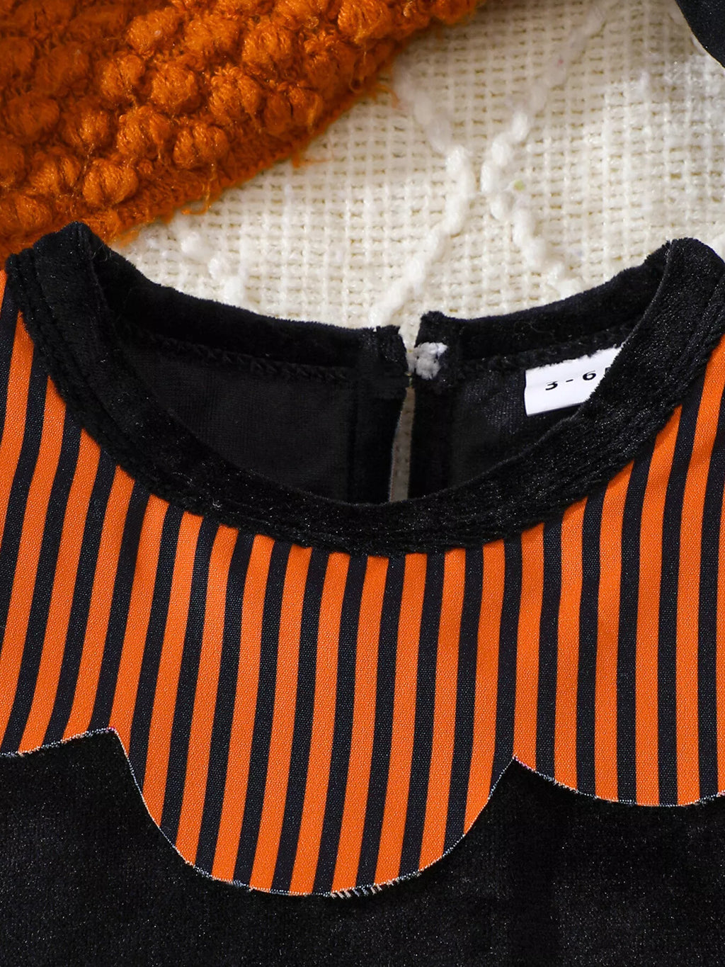 Orange and black striped yoke and black collar on the Halloween baby bodysuit