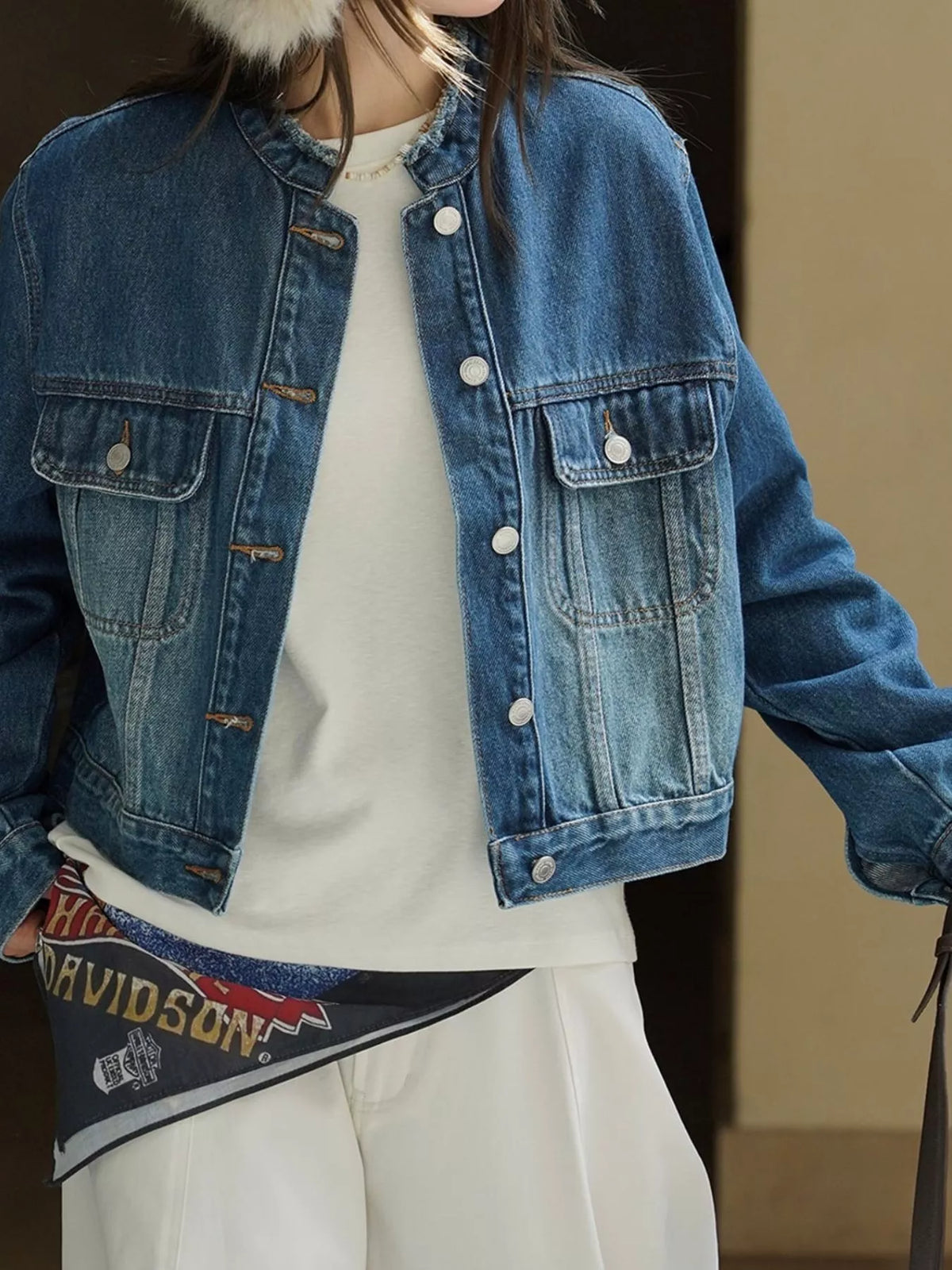 Blue cropped denim jacket worn open over a white top.