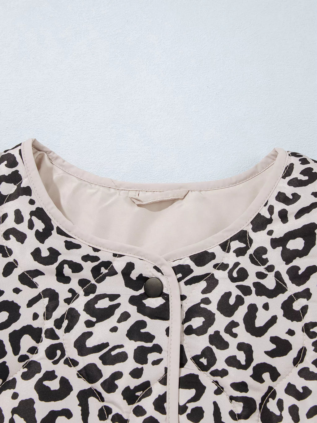 Close-up of the leopard-print jacket's round neckline and contrast binding.