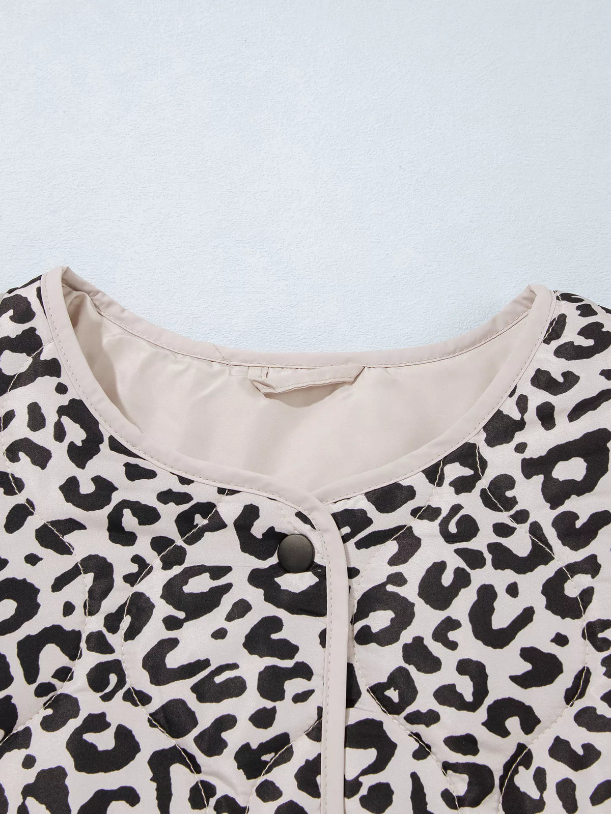 Close-up of the leopard-print jacket's round neckline and contrast binding.